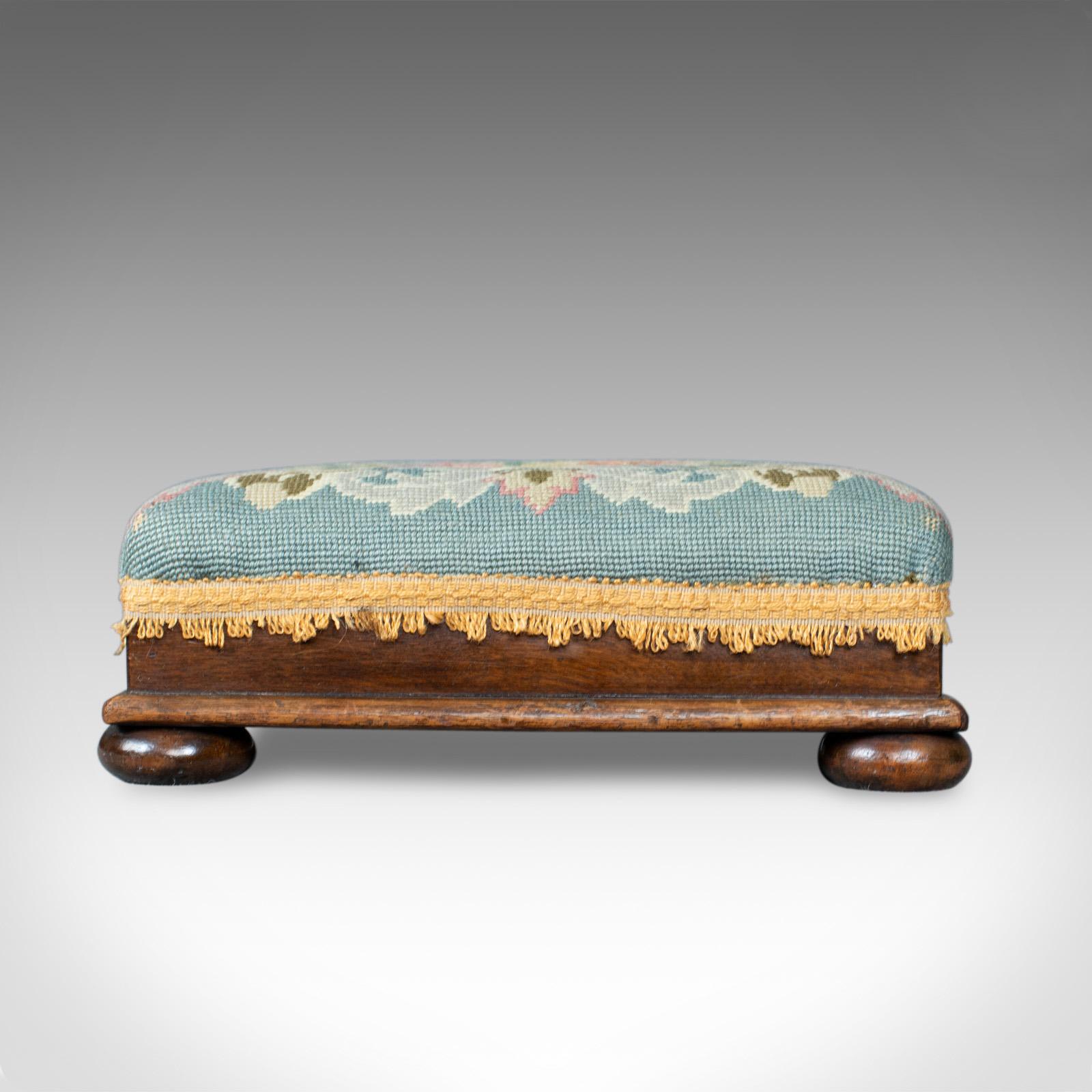This is a square antique footstool. An English, Victorian, needlepoint, carriage footrest dating to the late 19th century, circa 1890.

Traditionally stuffed and finished in a needlepoint cloth
Some desirable wear to the floral pattern
Trimmed