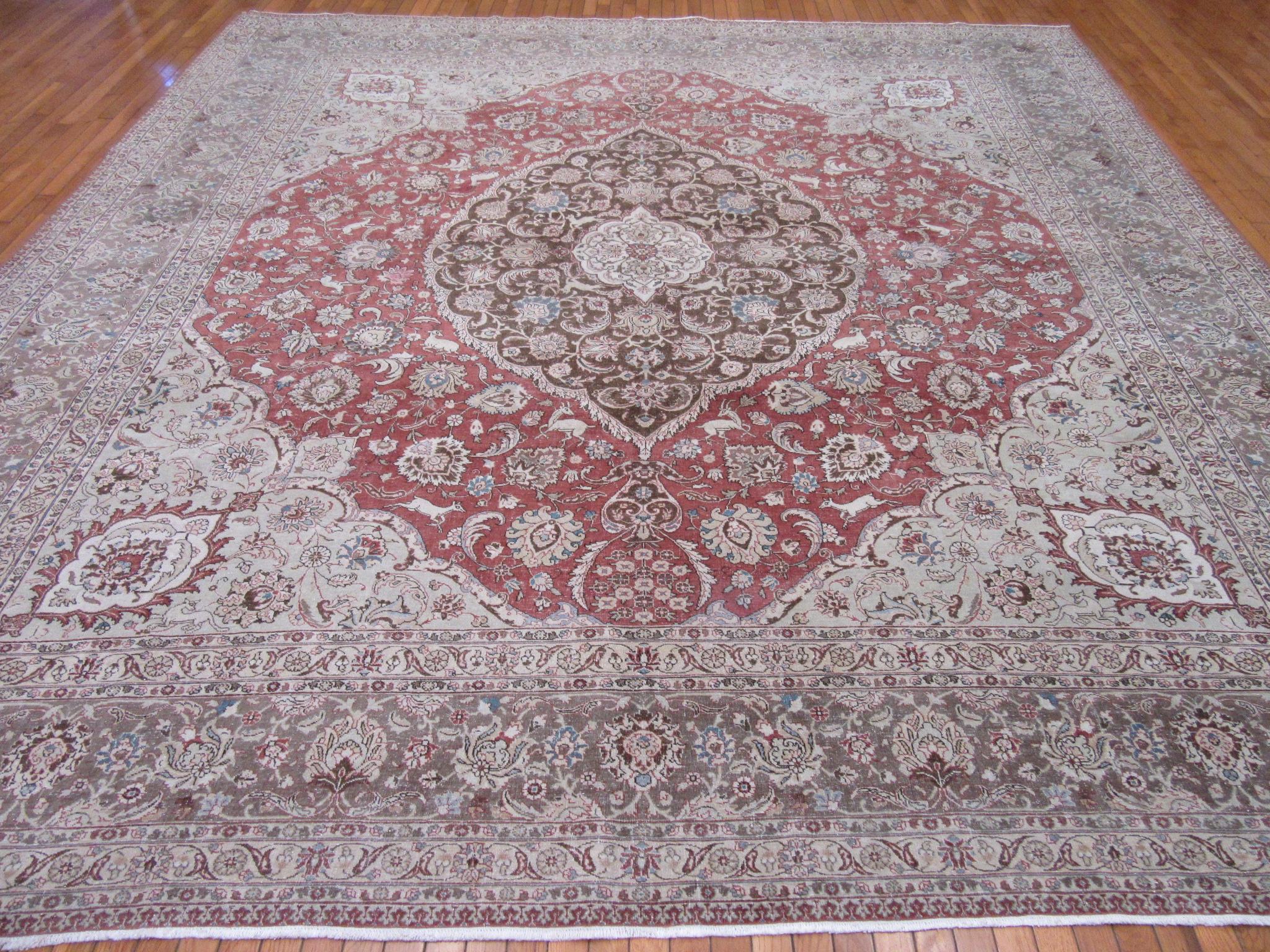 This is an antique hand knotted rug from the city of Tabriz in northwest Iran (Persian) that has been antique washed for softer tones. The rug has a detailed floral pattern with animal motifs on a soft red color field. It is finely hand knotted in