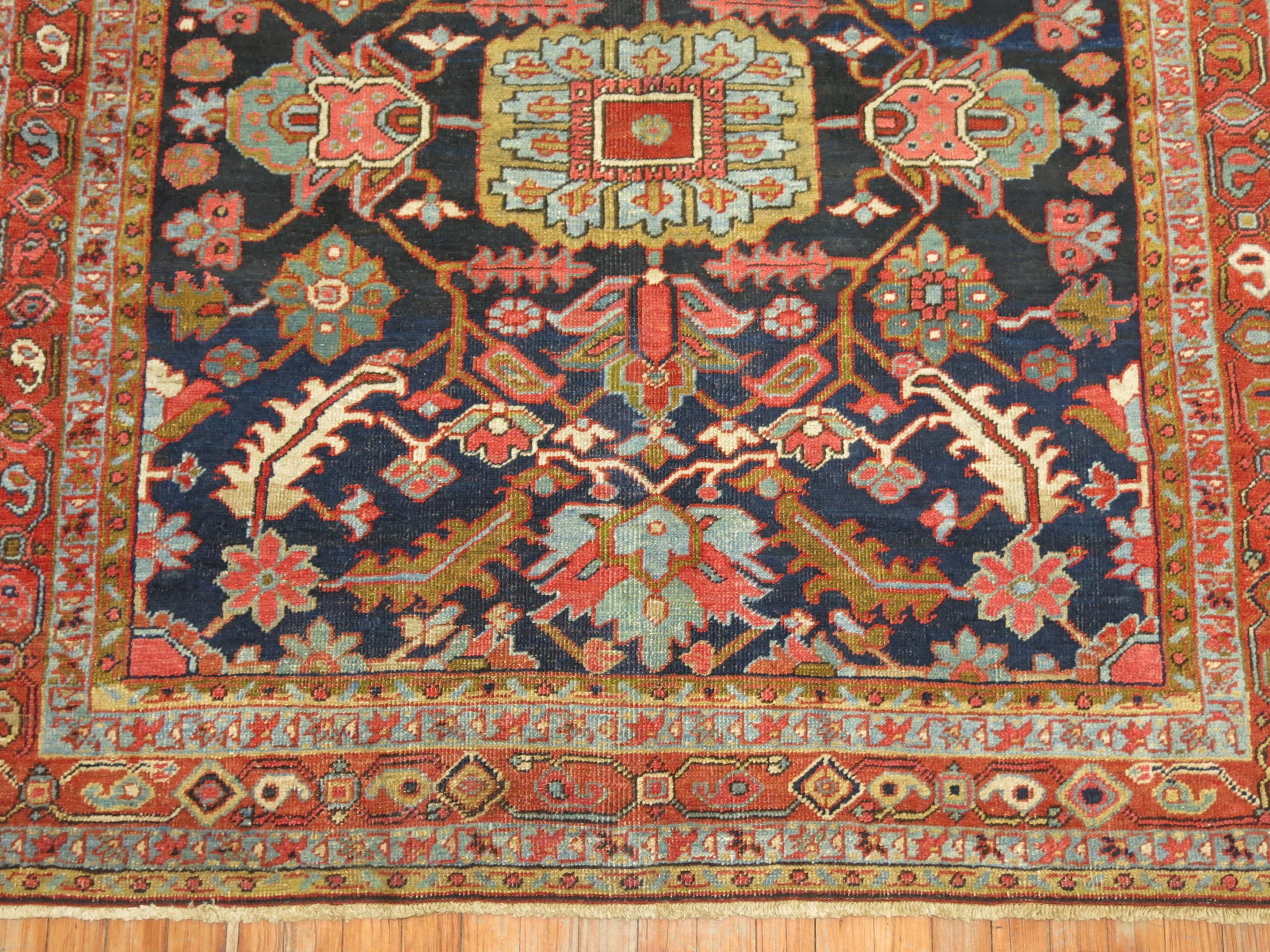 Colorful antique Persian Heriz Karadja rug with a floral and geometric motif on a navy blue ground.