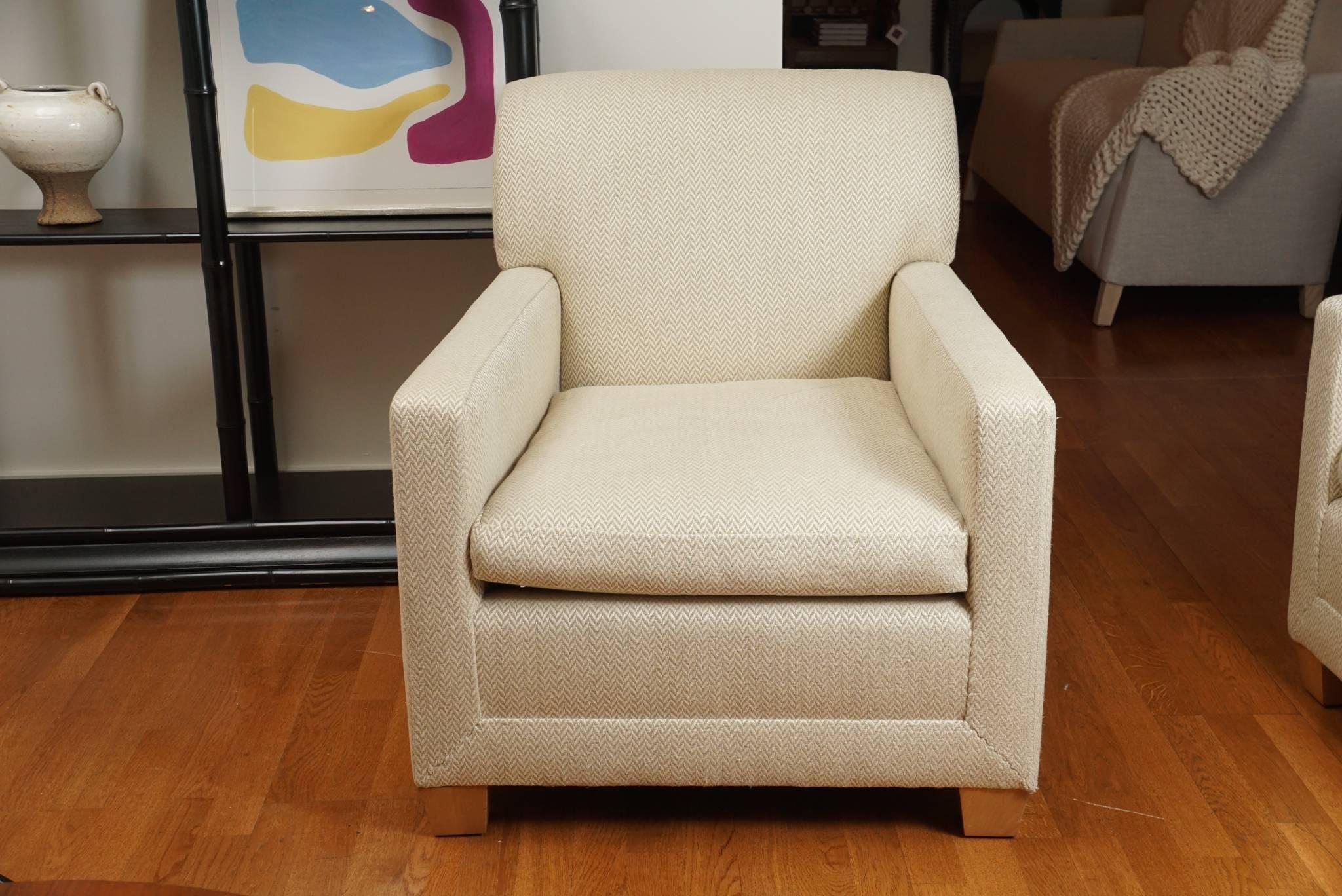 Comfortable, upholstered armchair, in a pleasing cream and beige, chevron style fabric, on light stained, beech wood feet.