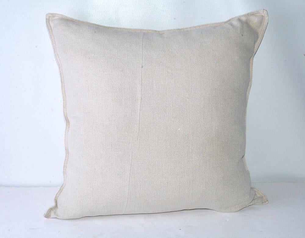 The square beige linen pillow is decorated with a series of printed French words and names. Top: 