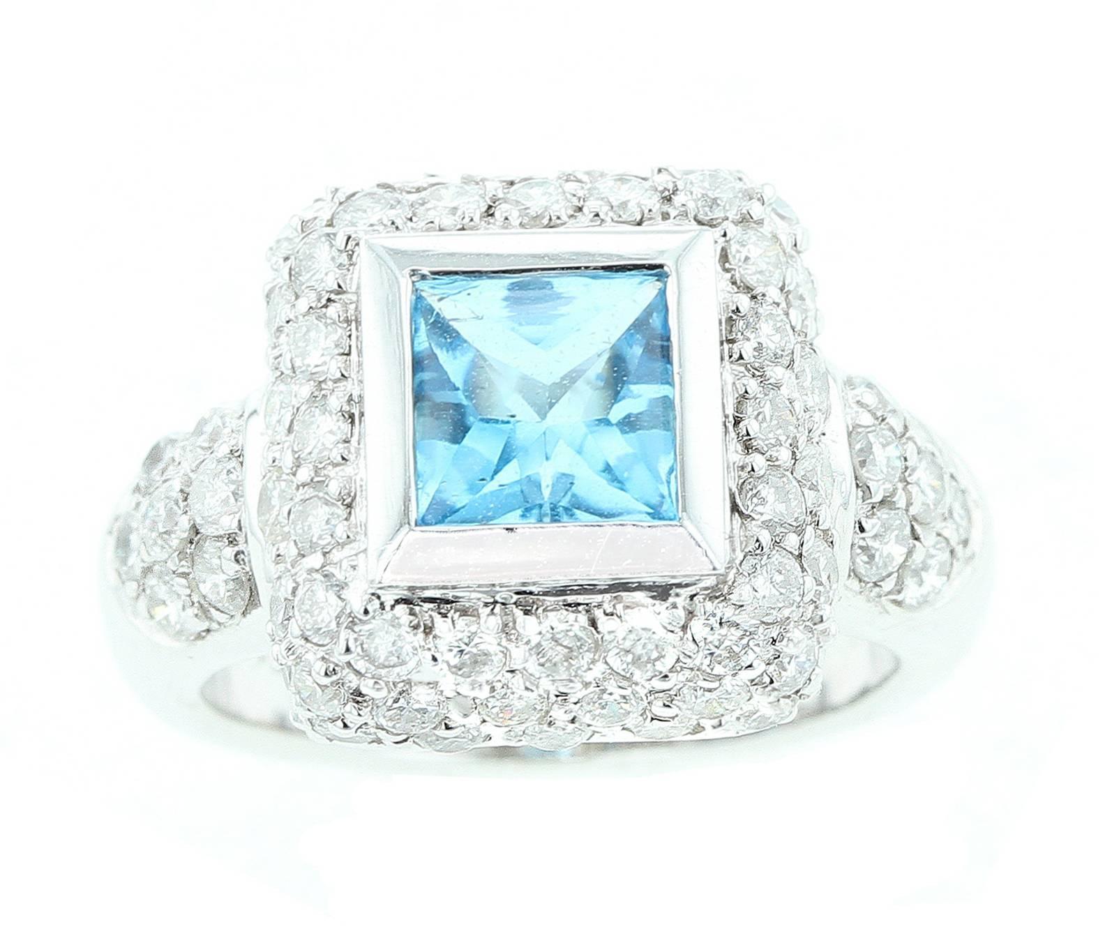 A square shape blue topaz with a white gold border accented with white round diamonds on the base and on the sides of the mounting. Set in 18K White Gold. Size 5.25.