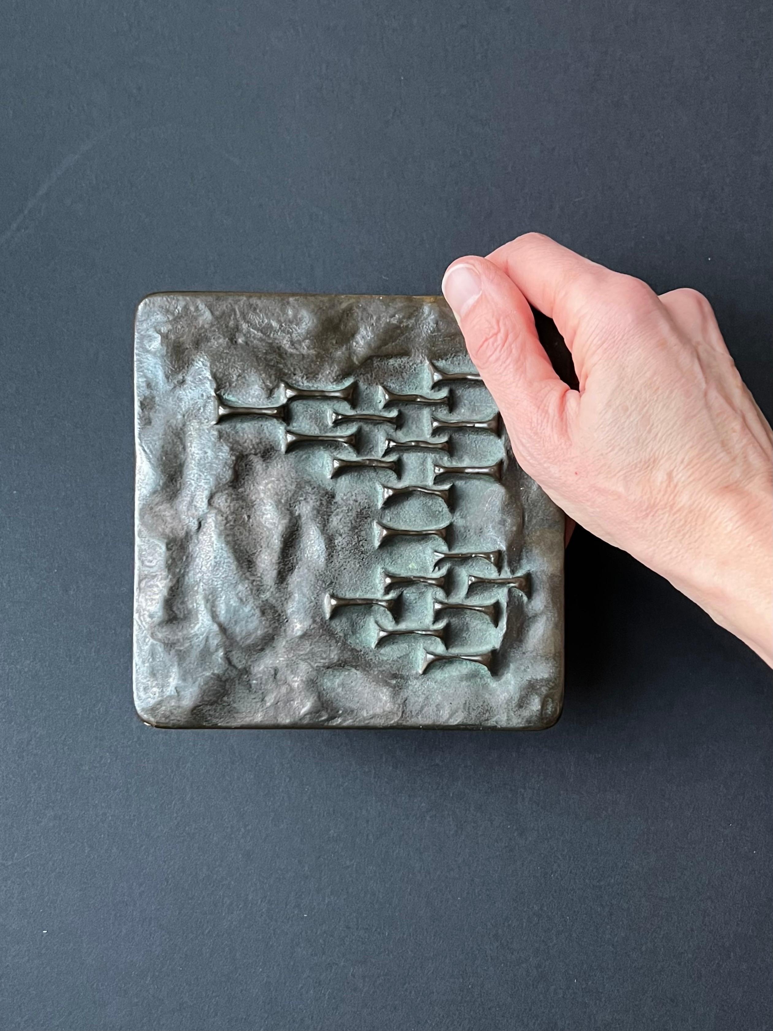 Maniglia quadrata per porte a pressione con disegno astratto in rilievo realizzata in bronzo fuso. Metà o fine del XX secolo, trovato in Germania.

Un bel pezzo pesante con una patina scura applicata. Ci sono segni di usura, tra cui il cambiamento