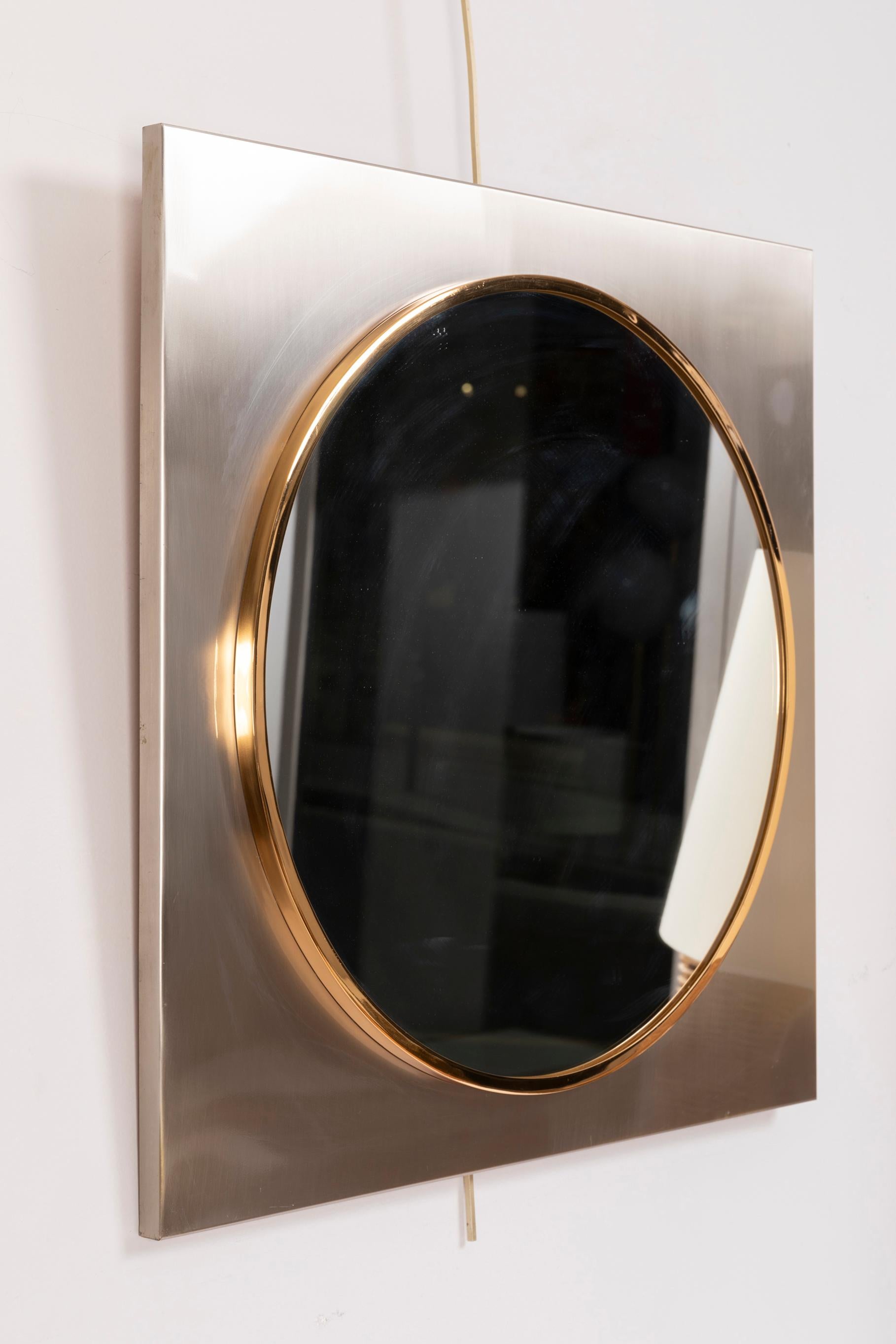 Square brushed steel framed, and round brass mirror.
The high quality fabrication reminds Jansen production.
France, 1970s

Dimensions: 
Height 60 cm, 23.6 in.
Width 60 cm, 23.6 in.
Depth 2 cm, 0.8 in.

      