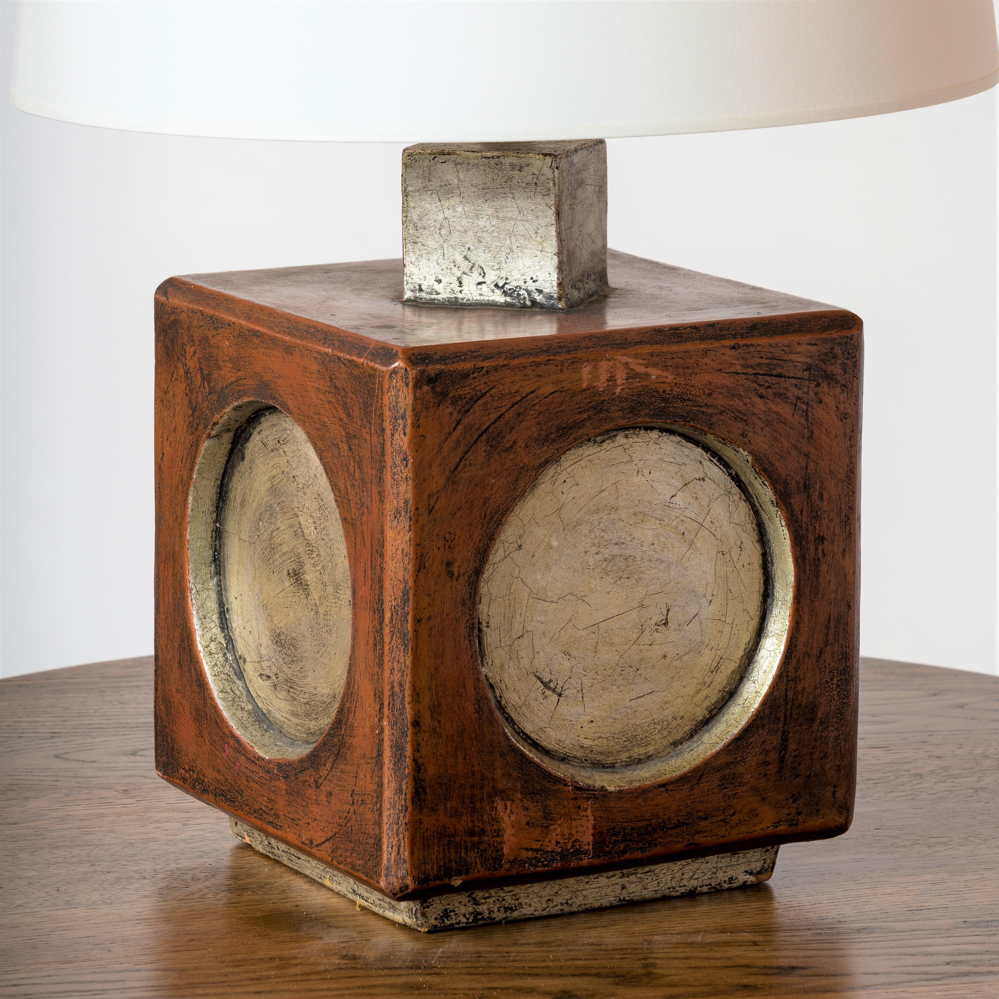 Square and faceted Italian brutaist terracotta lamp. Ochre painted base with silver painted circles on each of the four sides. 
Minor dents on base and on one edge.
European socket and wiring.
Shade for showing purposes.
This lamp will ship from