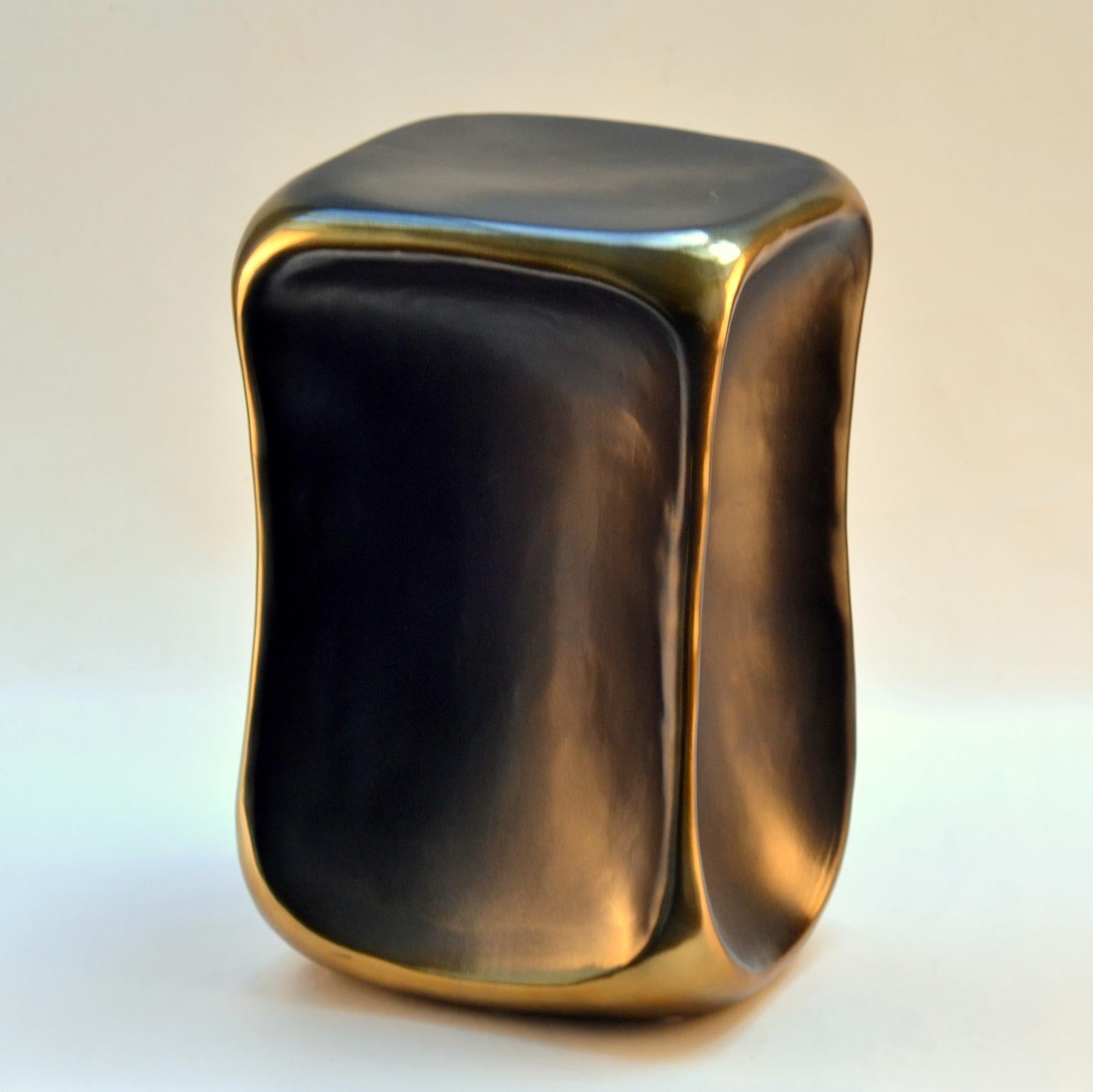 Sculptural black and gold side table with square top and rounded corners and accented golden ribs is cast in ceramic.