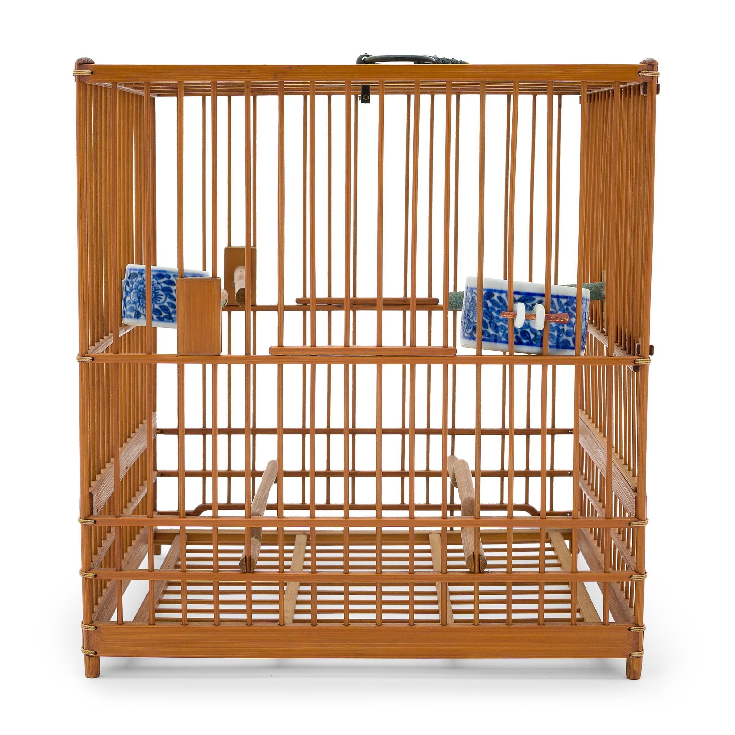 This well-proportioned birdcage is a feat of craftsmanship, carefully assembled of thin bamboo rods and held together by precise joinery and a bit of string. Two humpback perches run the length of the cage at the bottom, surmounted by three shorter