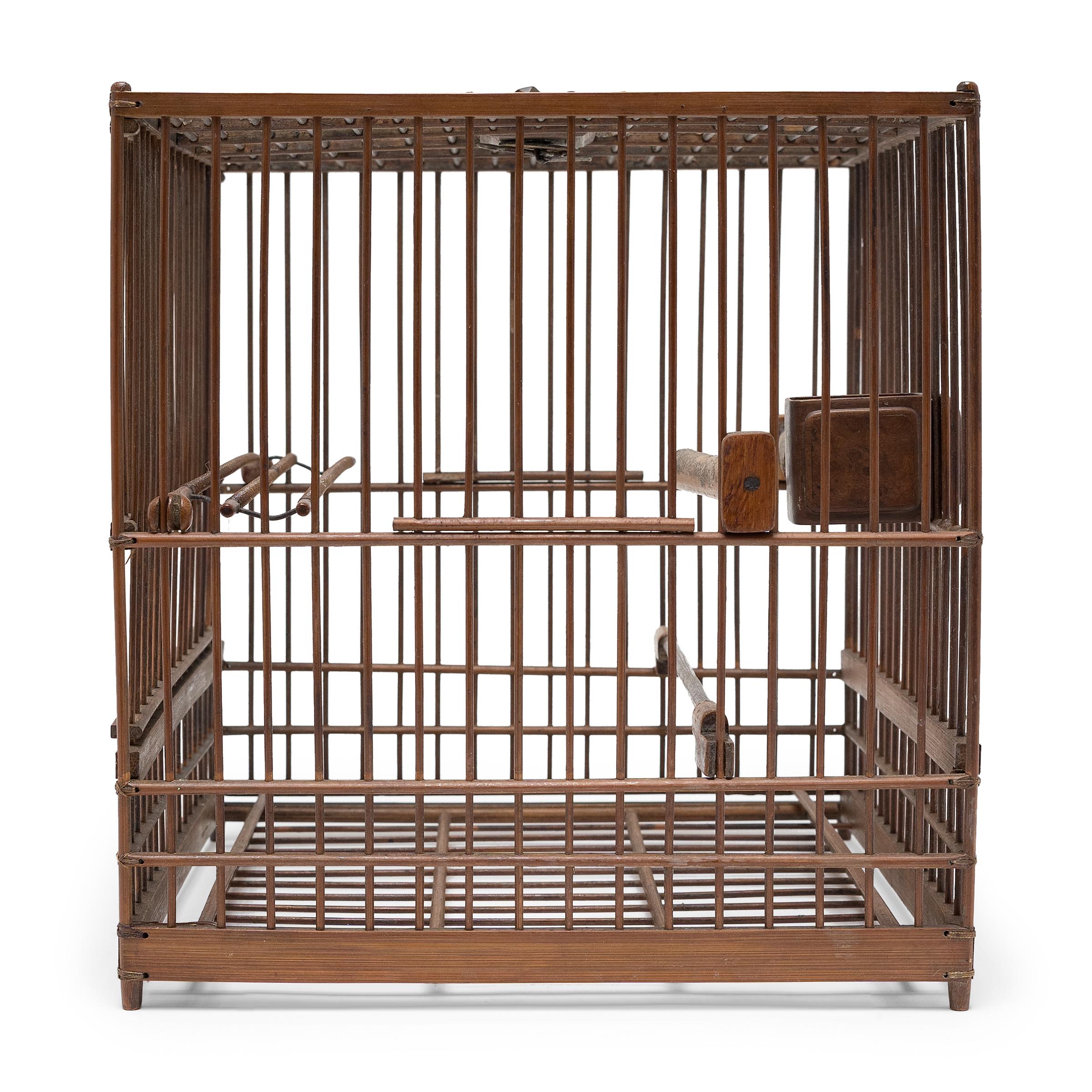 This delicate 19th-century birdcage was once home to the tiny pet bird of a Qing-dynasty aristocrat. The square cage is expertly crafted of thin bamboo rods and held together with waxed thread at the corners. The cage opens by a sliding side door