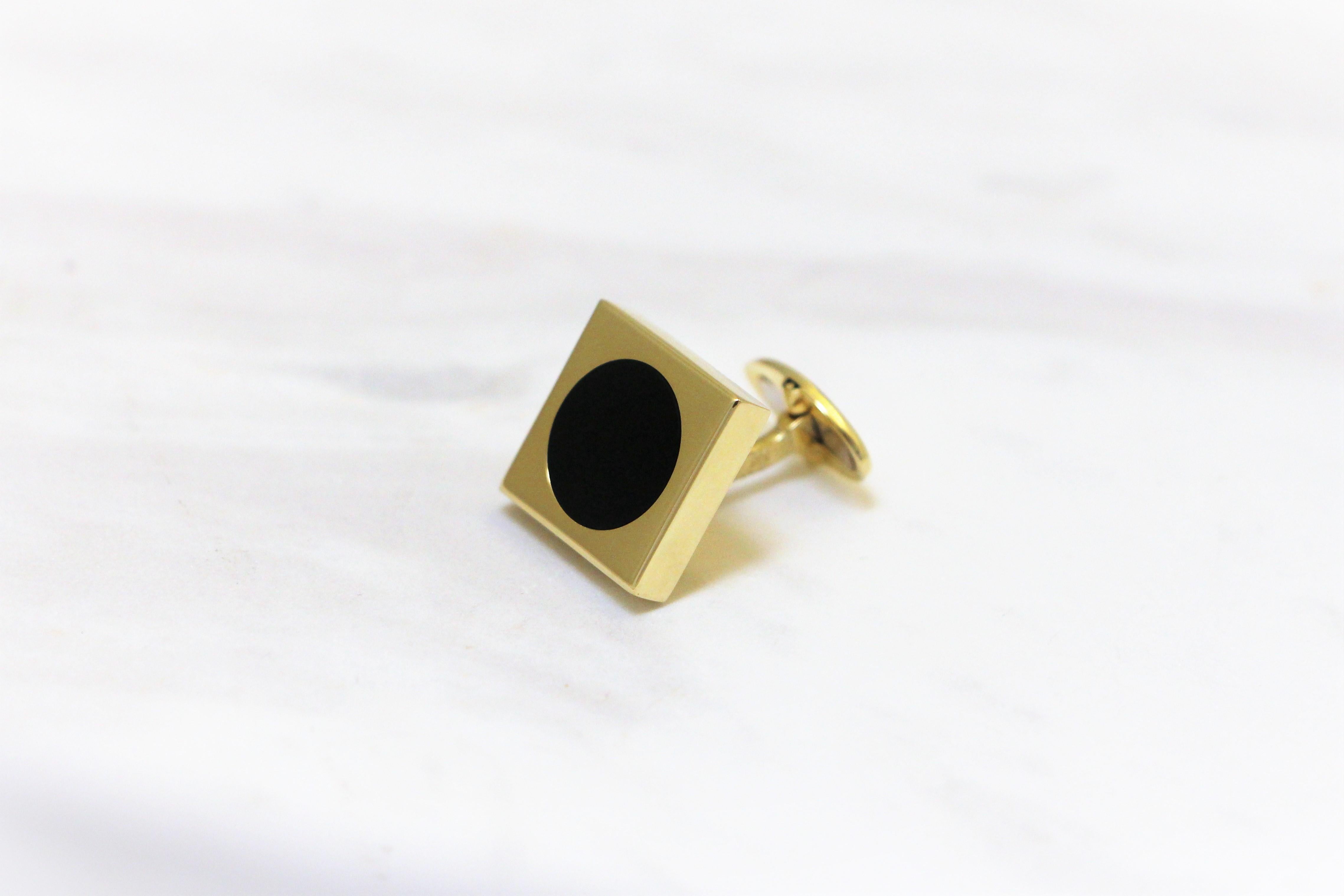 Quadratische Manschettenknöpfe aus 14 Karat Gelbgold, mit einem runden schwarzen Onyx in der Mitte.
Das Gold und der runde schwarze Onyx bilden zusammen ein zeitgemäßes Statement der Eleganz. Diese Manschettenknöpfe gehören zur Kollektion