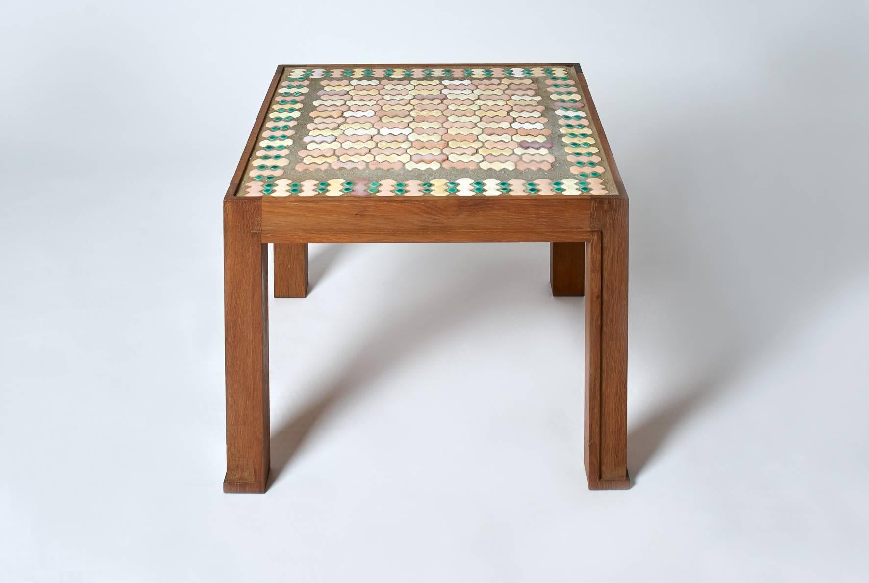 Jacques Lenoble (1902-1976) and Jacques Adnet (1900-1984)

A square coffee table in oak, tabletop with small pink shades enameled ceramic cruciate tiles fully fixed in cement. 
Bears a label on the back,
circa 1940.
Measures: Height 45 cm,