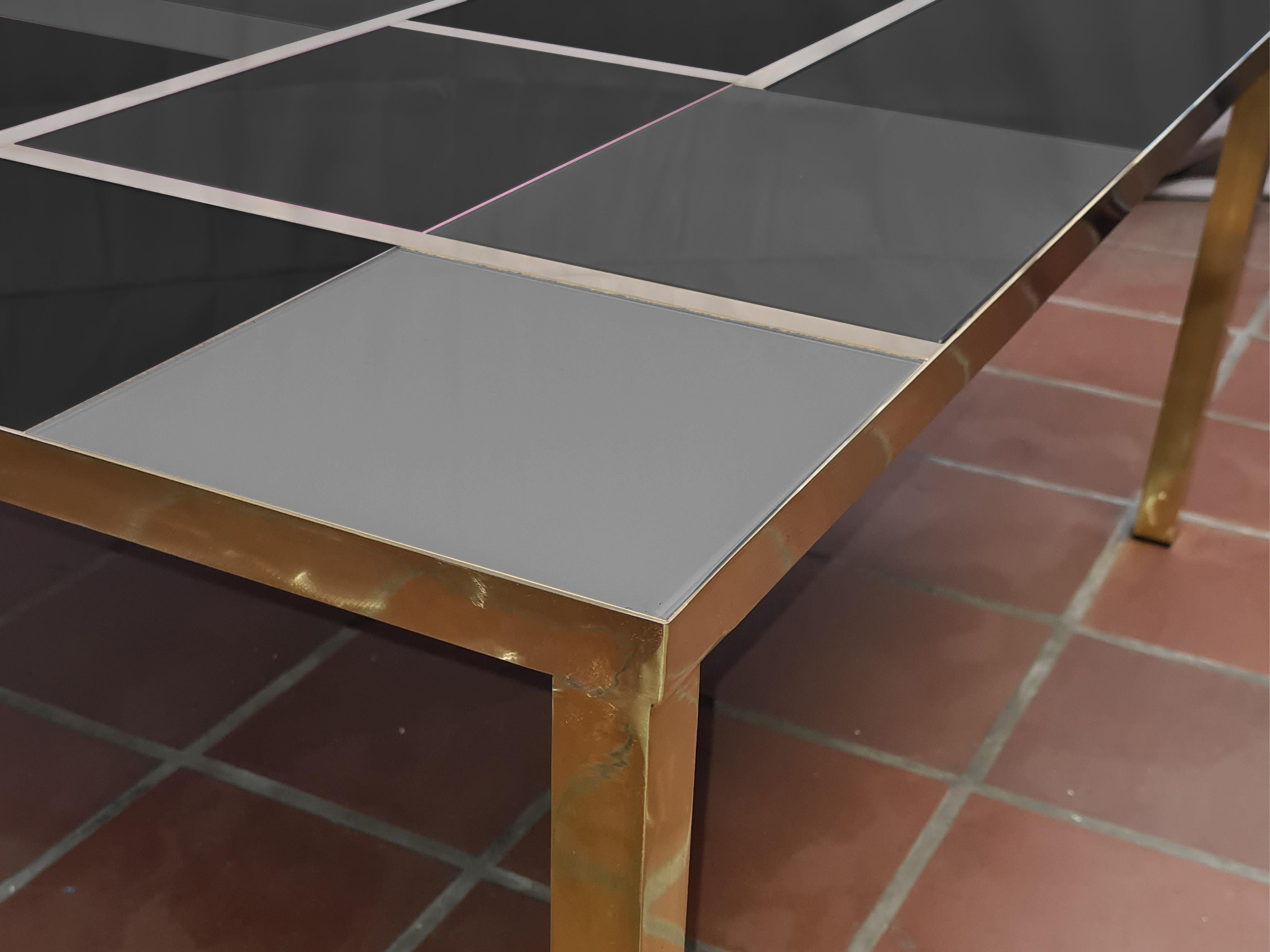 This square coffee table features a stunning gray and black Murano glass top, elegantly set in a durable brass frame. 

Handcrafted in Italy, this piece embodies mid-century modern style, showcasing artistic design through its unique glass patterns