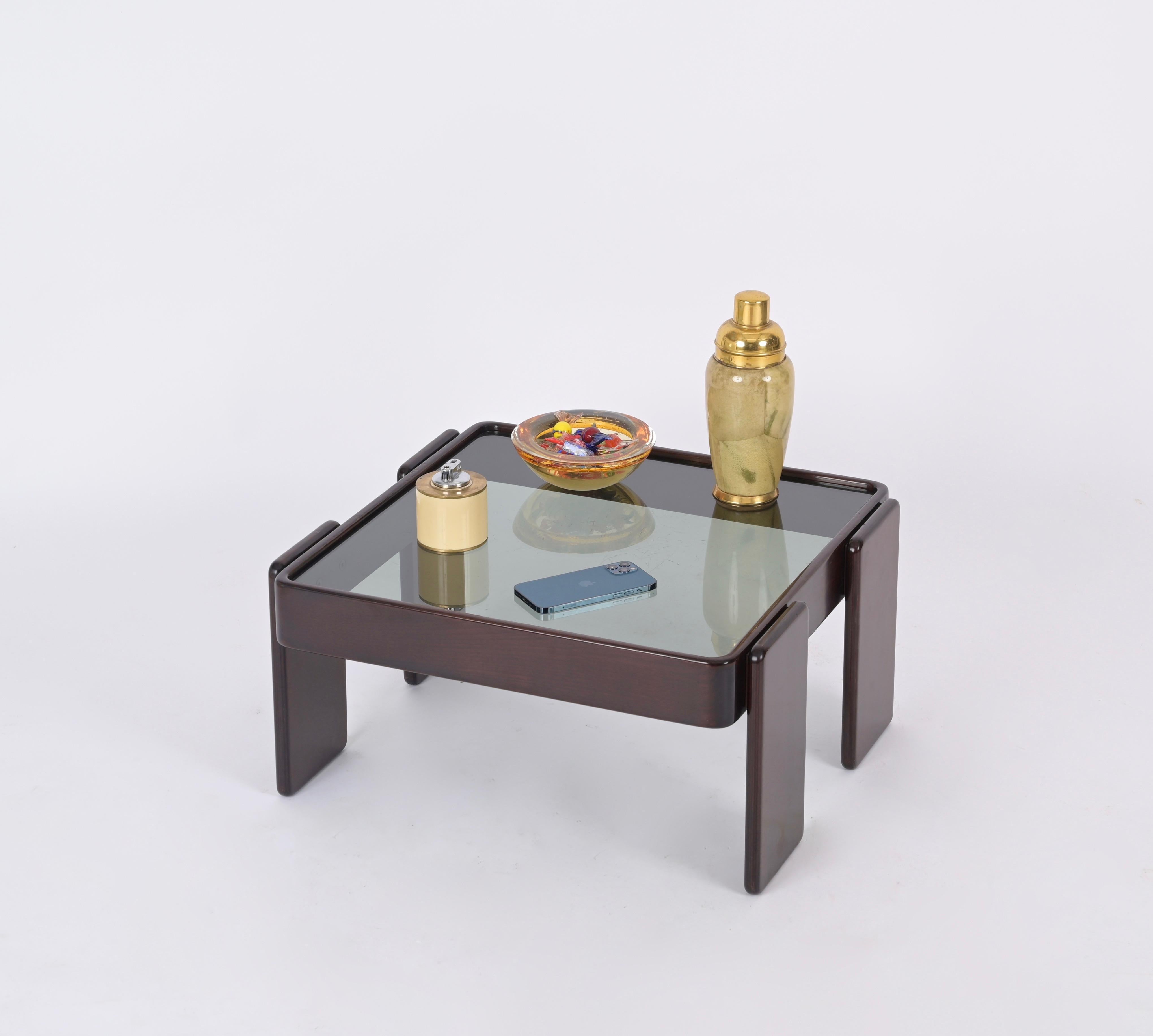 Superbe table basse carrée du milieu du siècle en bois de noyer avec plateau en verre fumé. Cette table basse emblématique a été conçue par Gianfranco Frattini pour Cassina, en Italie, dans les années 1970.  

Cette table basse élégante présente une