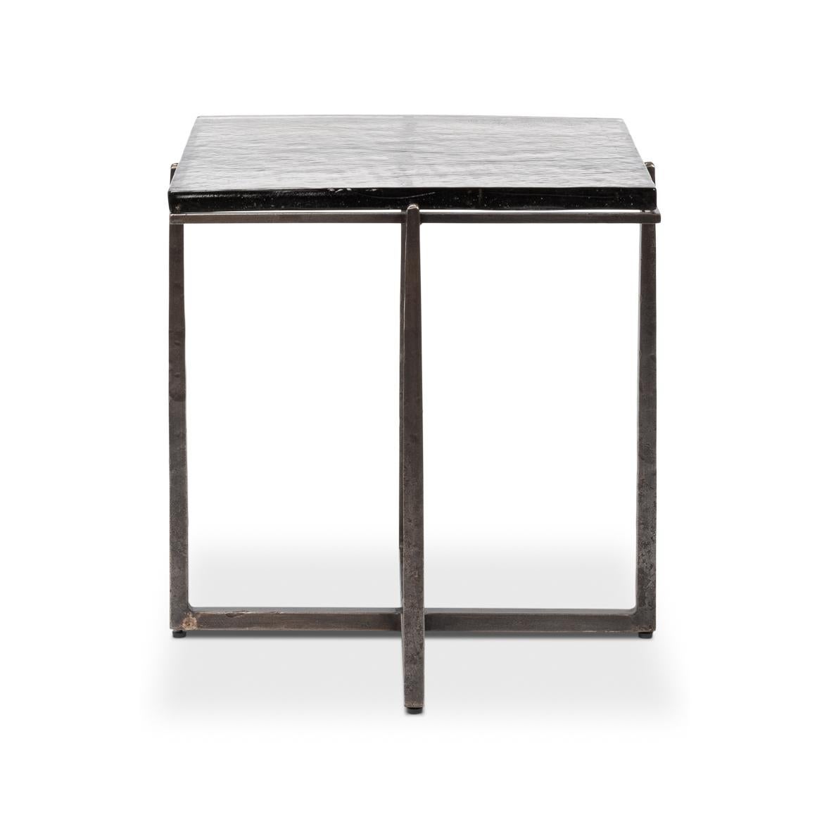 This exquisite piece features a hand-forged iron base in an aged nickel finish, lending a touch of vintage elegance while maintaining a sleek contemporary aesthetic. The casted glass top, with its organic texture, adds depth and character,
