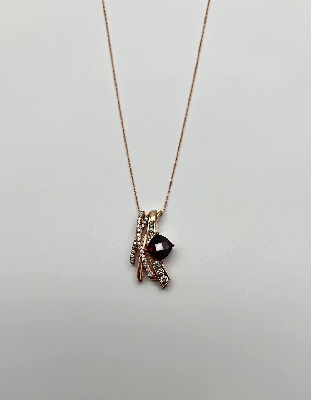 Elegant pendant necklace featuring a striking design. Crafted with precision, the pendant showcases a large, faceted red garnet at its center. Surrounding the gemstone are intertwining gold bands, adorned with sparkling white diamonds, creating a