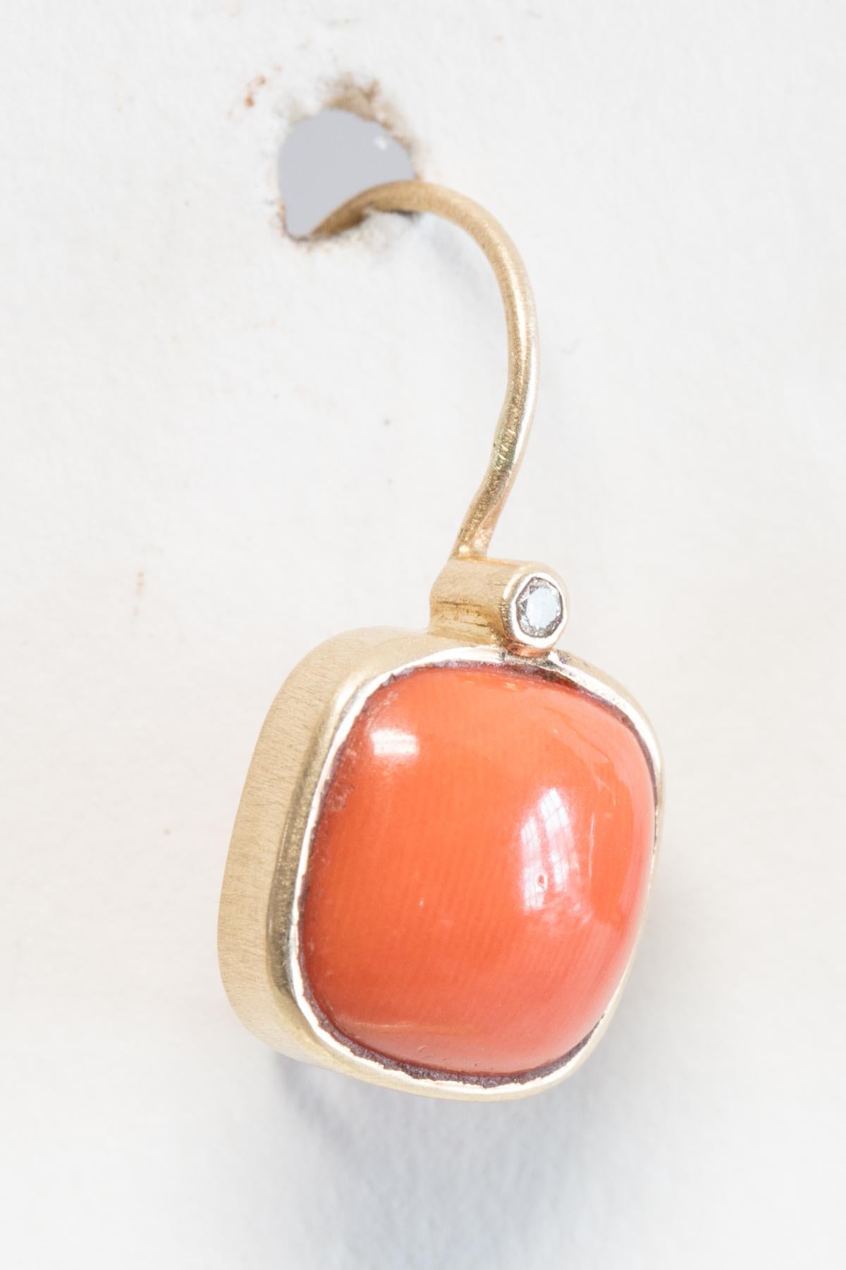 Square cut Italian coral bordered in 18K gold with faceted solitaire diamond at the top.  On French wires for pierced ears.