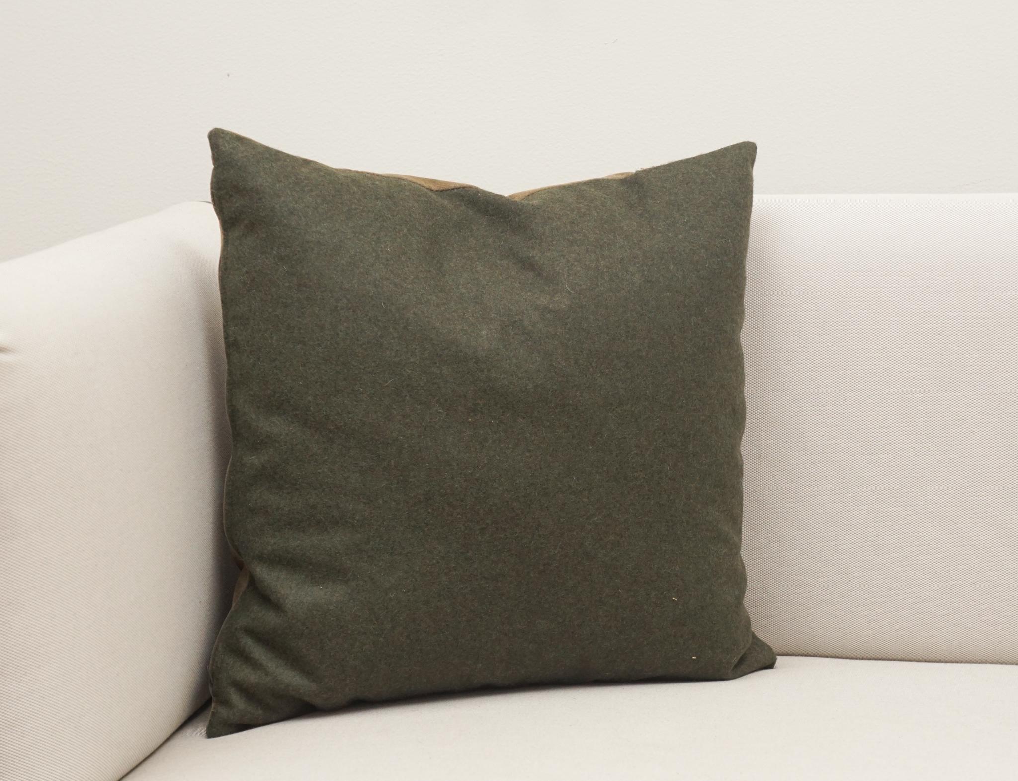 Le coussin en cuir de cerf, présenté ici, est fabriqué sur mesure en Autriche et n'est qu'un des nombreux modèles actuellement disponibles.  De forme carrée, la façade de l'oreiller en cuir de cerf Loden est ornée d'un galon coloré.  Le dos est fini