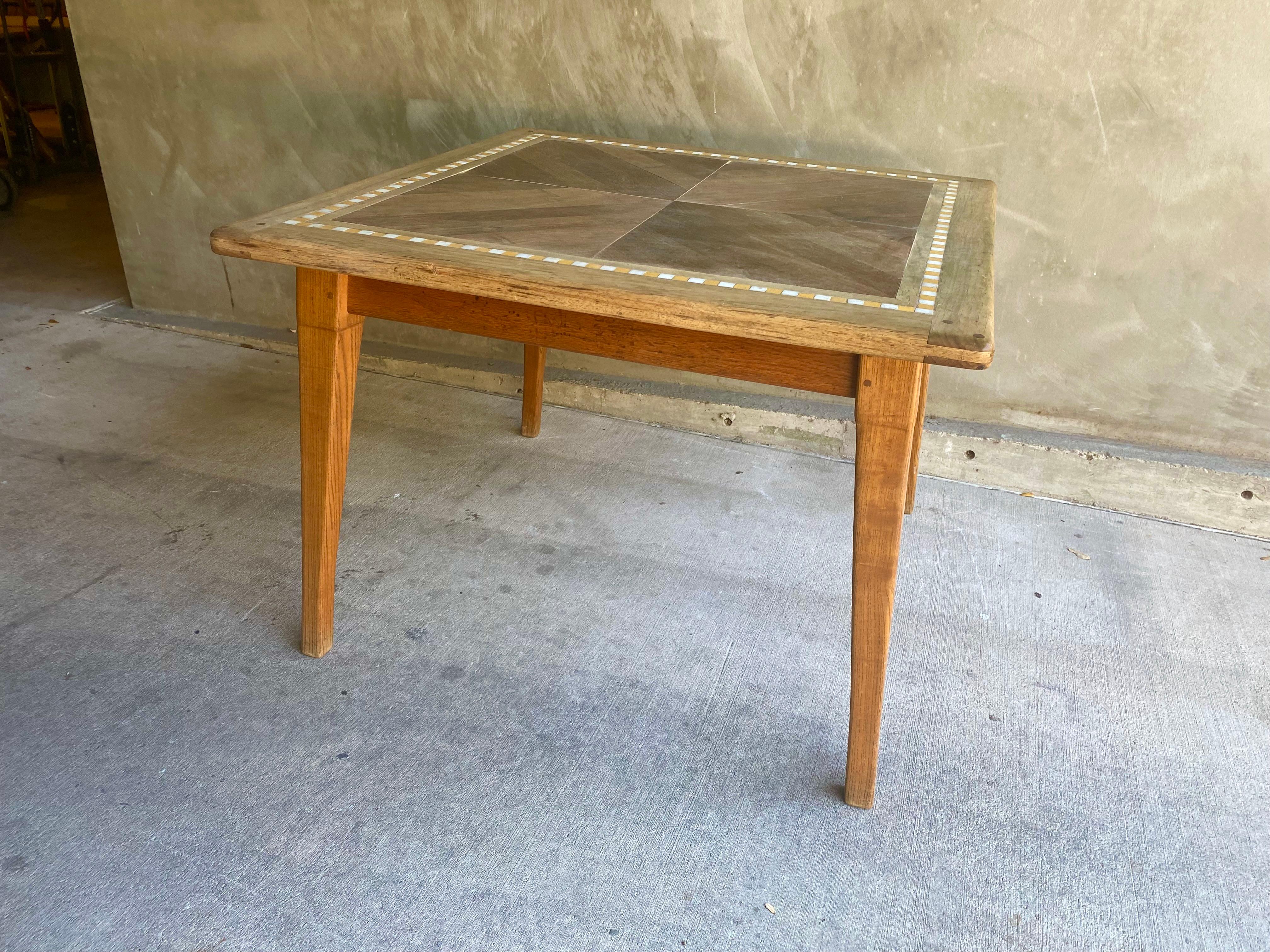 Clean lined French mid-century dining table, square, in oak with yellow/gold and white tile accent at perimeter. Inlayed top and angular legs. Perfect game table size. France, 1950's.
