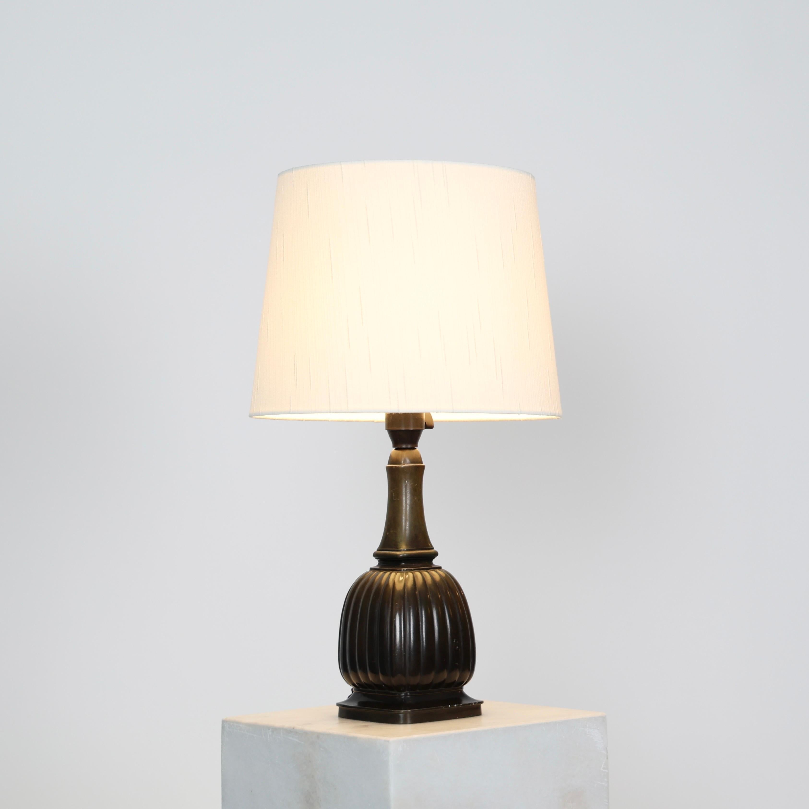 Timeless no. 1856 Table Lamp made by Just Andersen in the 1930s.
 
* Discometal table lamp with a square cannellated body, slim neck and white shade.
* Designer: Just Andersen
* Manufacturer: Just Andersen
* Style: 1856
* Year: 1936
* Condition:
