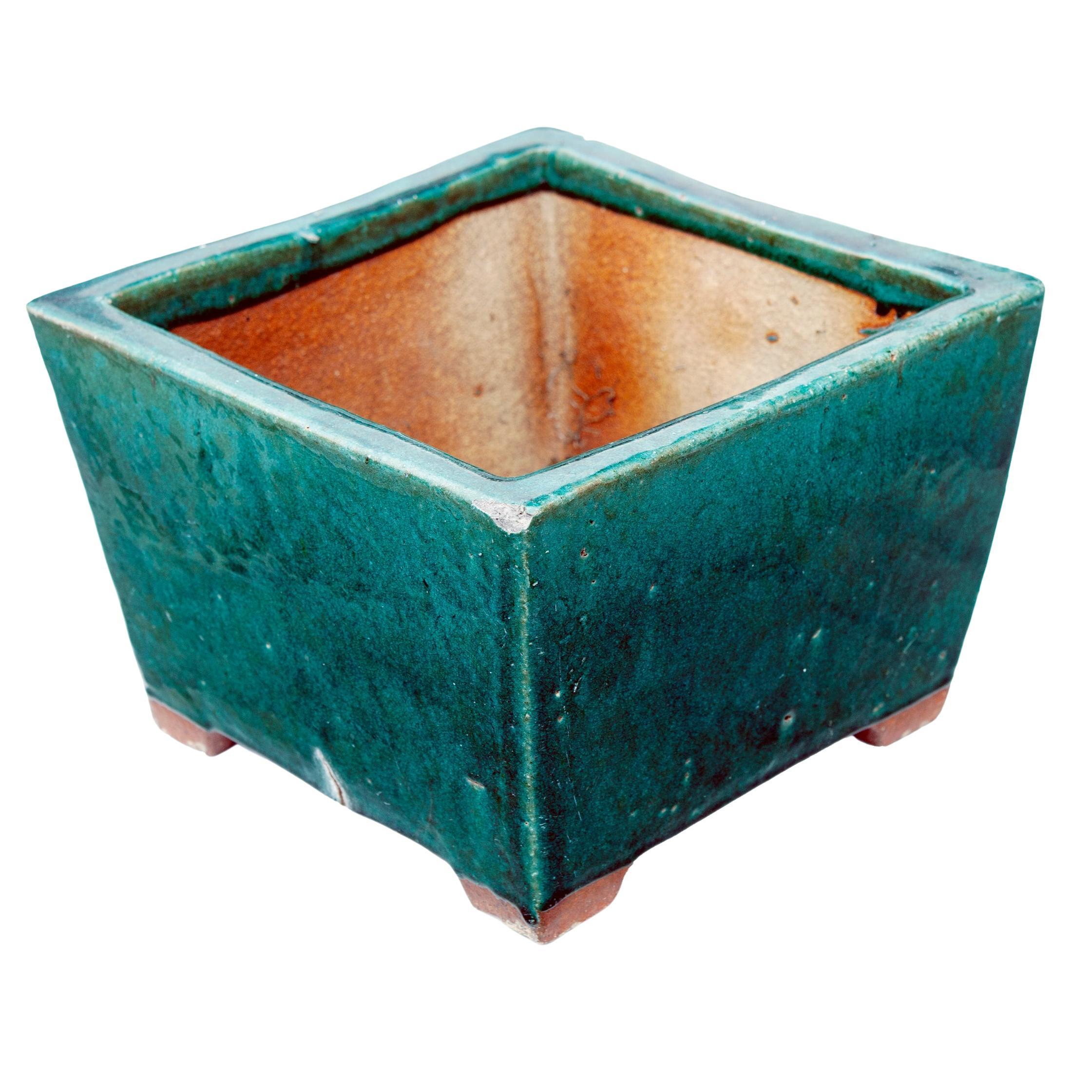 Ein quadratischer Pflanzkübel aus Terrakotta im Vintage-Stil mit einer smaragdgrünen Glasur. Das Pflanzgefäß ist handgefertigt und hat eine gewellte Textur, ein einzigartiges und schönes Stück. Das Pflanzgefäß ist unsigniert, die quadratische Form