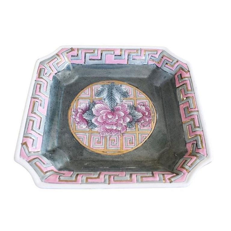 A beautiful famille rose trinket dish or catchall. Created from ceramic, this piece is square in shape, with scalloped corners. The interior of the dish is in a blue/gray glaze, with a pink carnation or lotus design at the center. The edges are