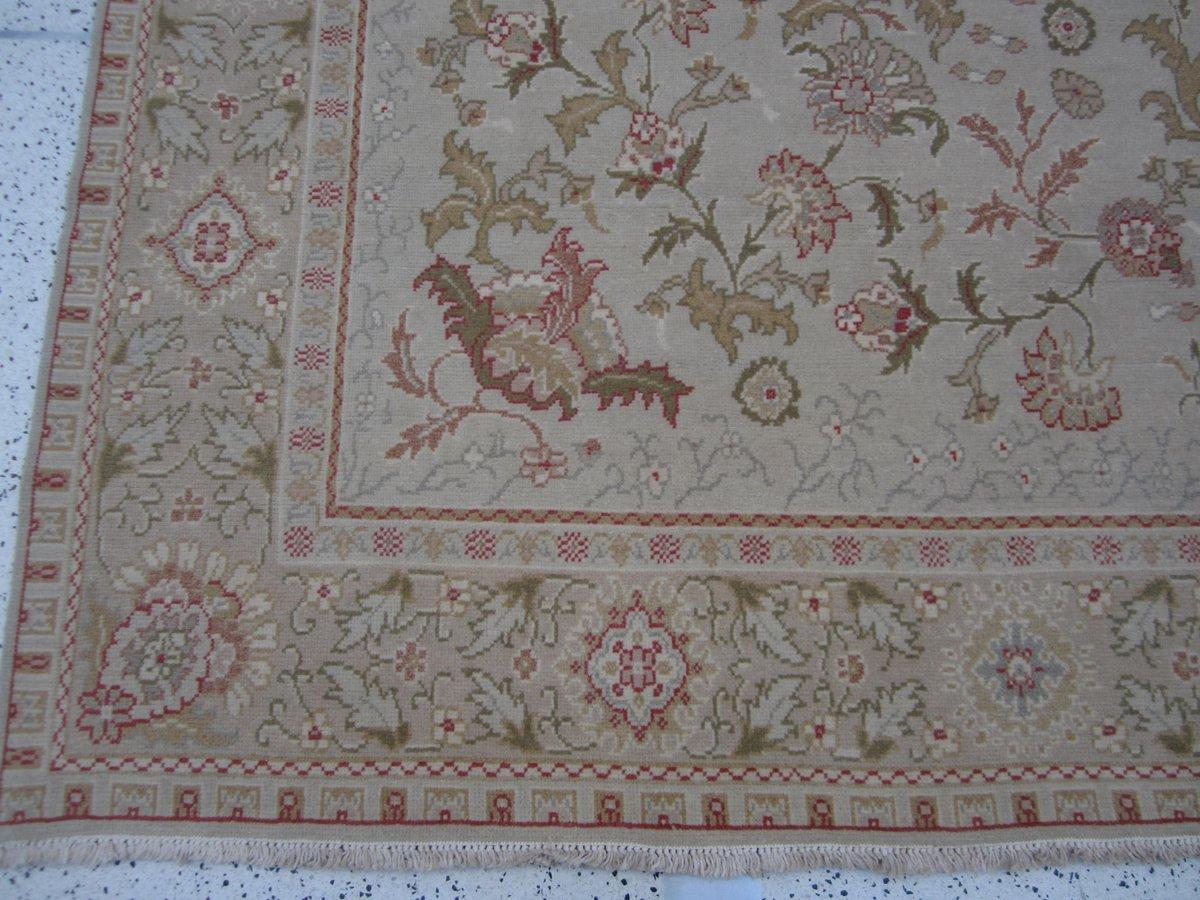 A traditional style in a not-so-traditional shape. A floral ribbon creates the fence for a charming garden of blossoms in this delightful square area rug. Red, coral, pink, gold and green against a neutral beige background. Hand knotted wool.