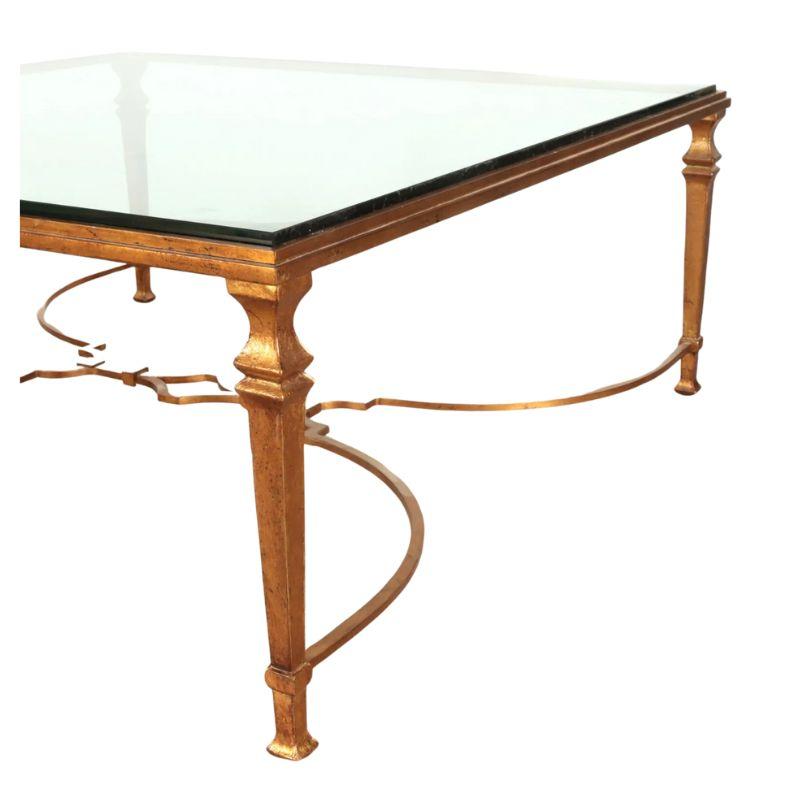Square gilt iron and glass top coffee table in neoclassical style with fluted, tapered legs and a curved X base stretcher that meets with an open geometric design.  An elegant and chic piece for a living space.