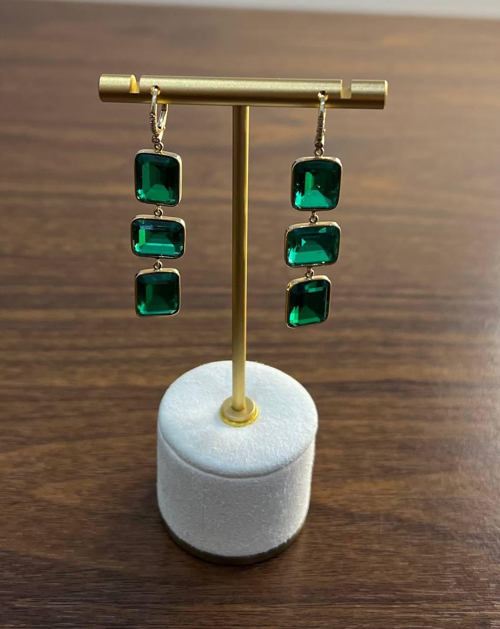 Un paio di eleganti orecchini a goccia con tre smeraldi verdi rettangolari per orecchino.

Le pietre hanno un colore verde intenso e vibrante, incastonate in un'elegante montatura d'oro.

Realizzati in oro 14k, questi orecchini trasudano