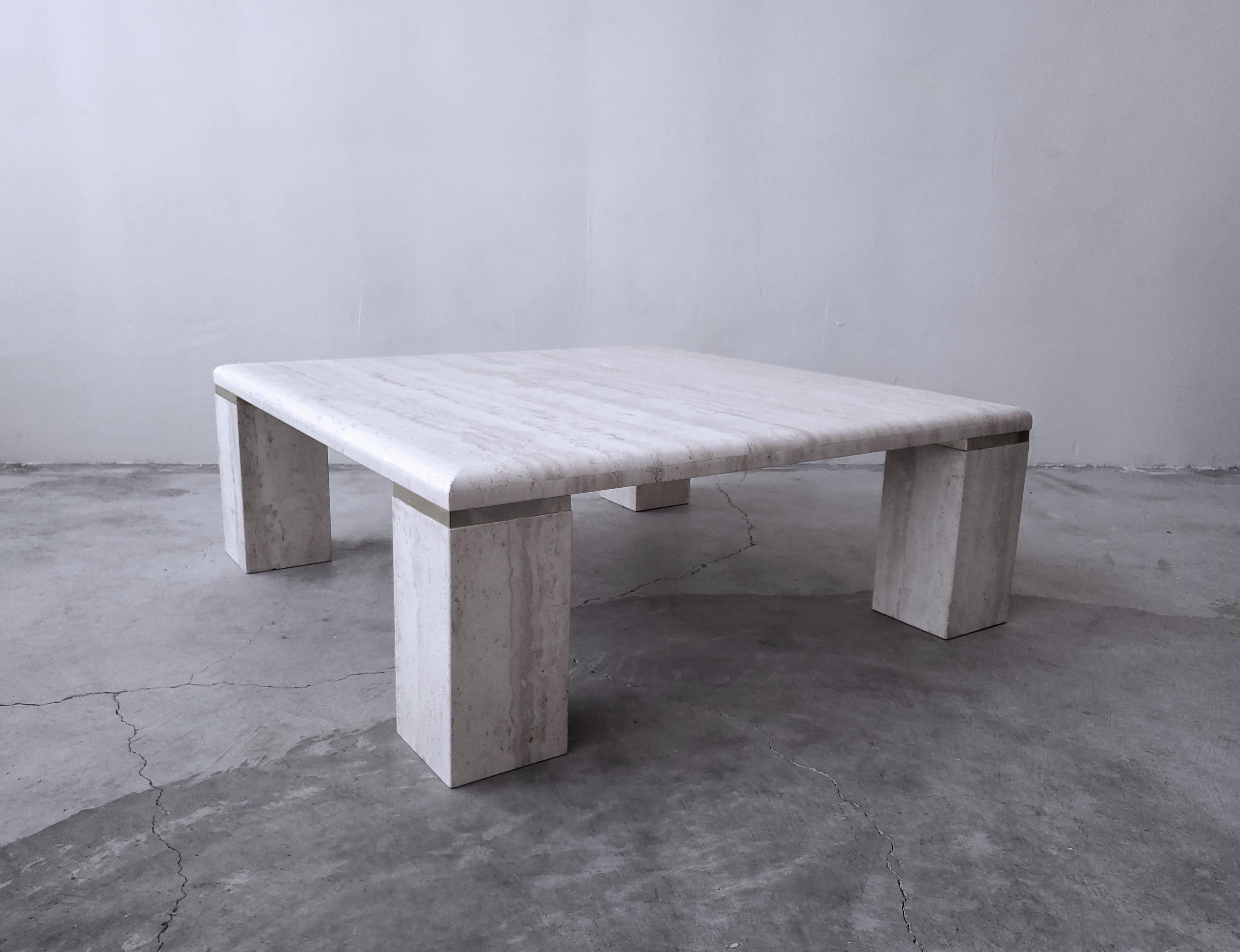 Very elegant, vintage square travertine coffee table. Simple, beautiful piece. Tabletop is a square with 4 large square legs that are manufactured with a nice brass separation detail, classing it up a bit more. 

Table is in excellent condition.