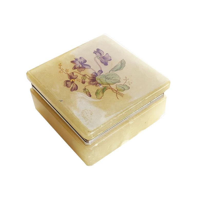A beautiful square yellow alabaster trinket box with a floral design. With a hinged lid, a lovely floral motif in purple and green decorates the top. The lid opens to reveal a circular well for storing jewelry or trinkets. We love it for holding