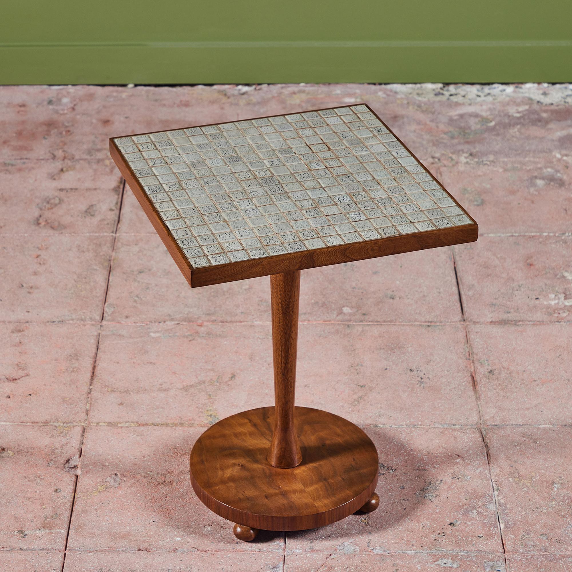 Square pedestal side table for Lane, c.1960s, USA. The teak table top is inlaid with square speckled ceramic tiles in gray and cream. The base of the table is a tapered teak dowel on a circular base with three ball feet.

Dimensions
15.5