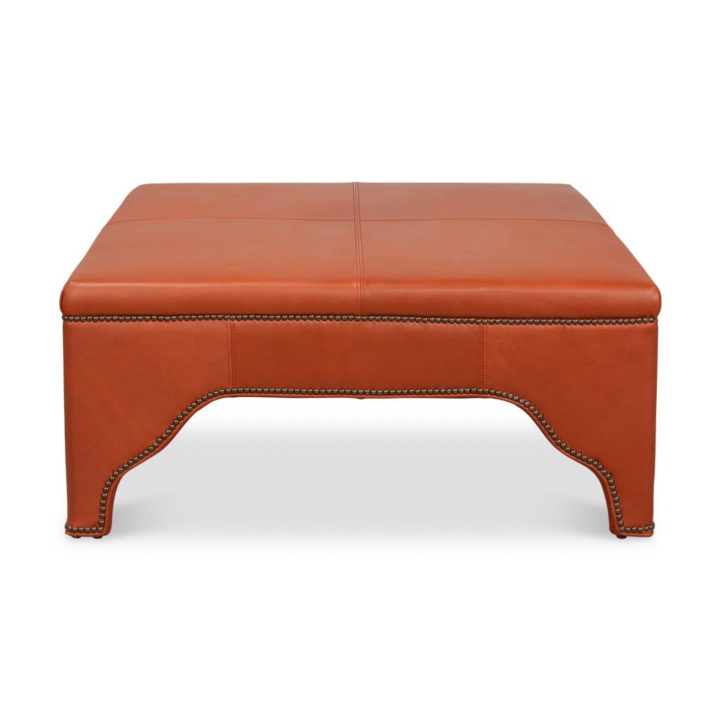 Recouvert d'un cuir riche et audacieux, il est doté d'un plateau lisse à panneaux qui peut servir de table basse élégante ou de siège supplémentaire. Son tablier festonné classique ajoute un élément de charme sophistiqué, tandis que la garniture de