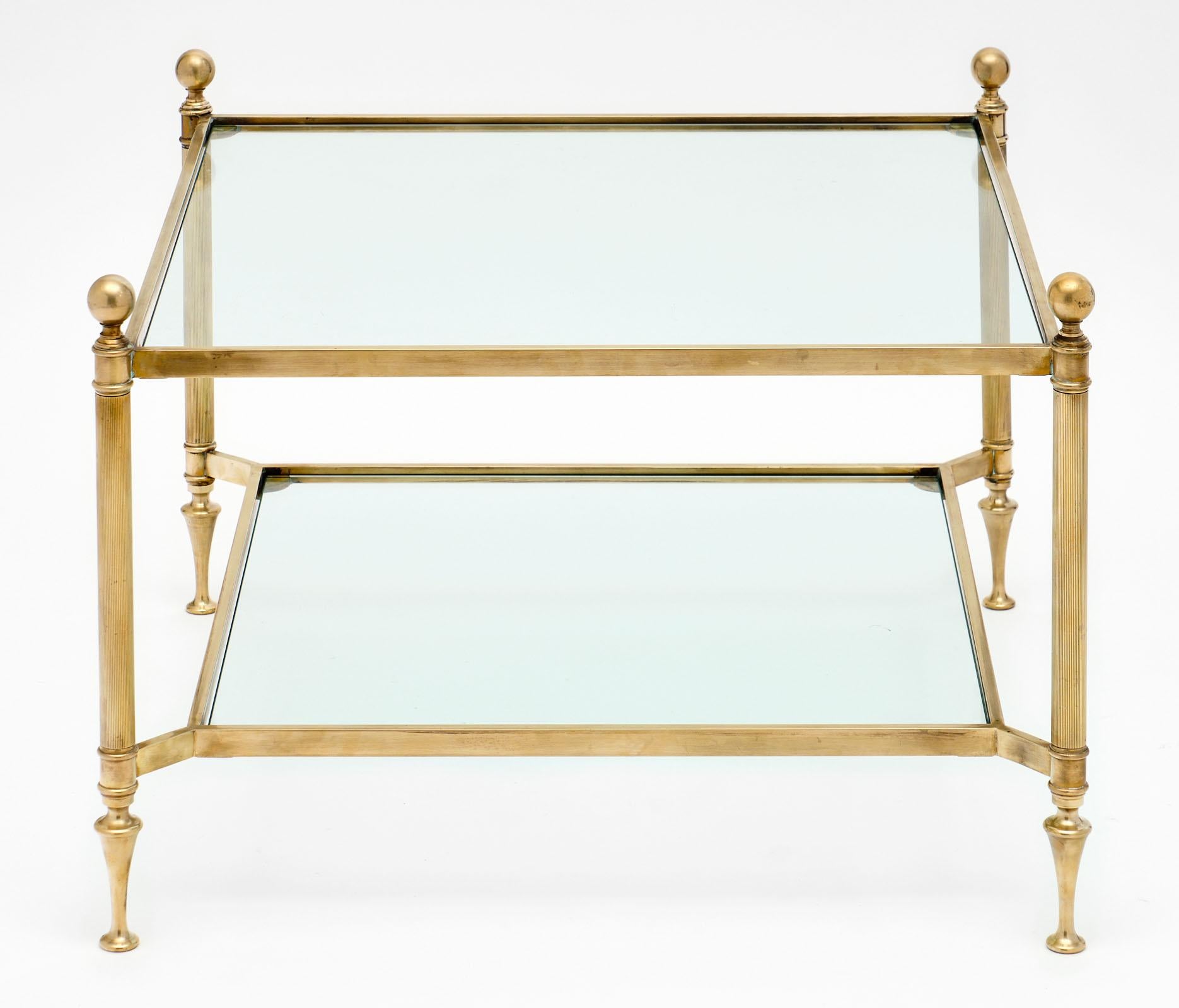 Maison Baguès square coffee table with a fine, gilt brass structure. The legs are ridged with spherical brass finials, and holds two shelves of clear glass. This could be used as a coffee table or side table.
