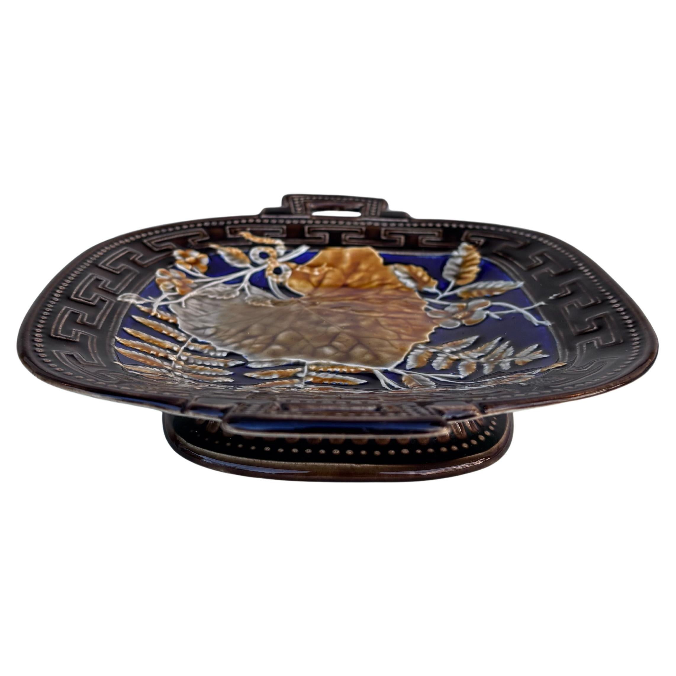 Soporte o comedero ovalado francés de mayólica con hojas, helechos y flores rosas, hacia 1880-1890, firmado Choisy le Roi.
9,8 por 8,2 pulgadas.
H / 2 pulgadas.