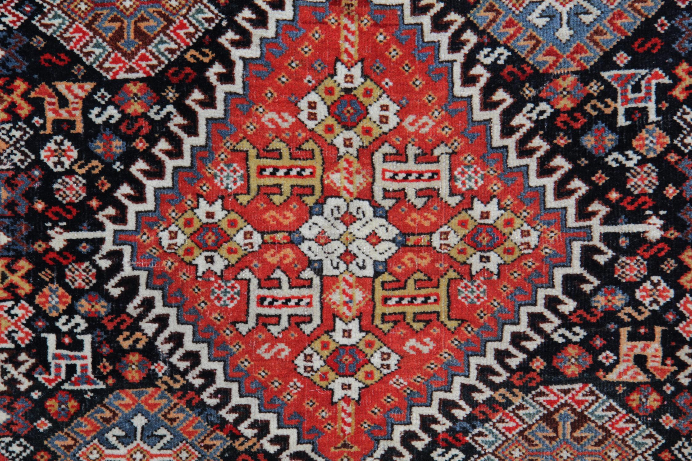 This beautiful rug is a great example of rugs woven in the 1880s. It features a red field with a unique central medallion, the diamond is then surrounded by smaller motifs and animal figures woven on a contrasting black background in accents of red,