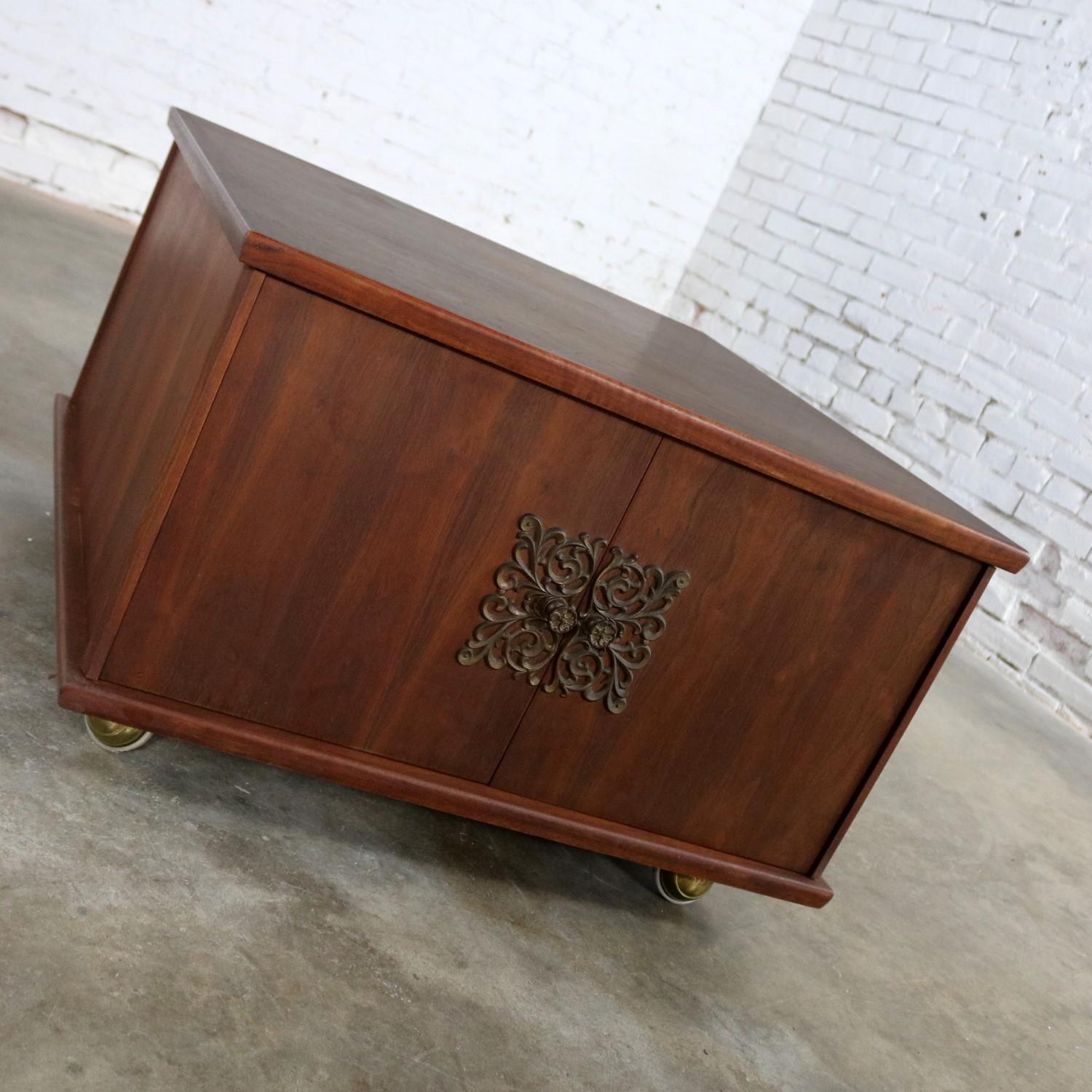 Handsome square midcentury rolling end table storage cabinet on brass ball casters with double opening doors with beautiful brass scrollwork escutcheons and pulls. This side table storage cabinet is in excellent vintage condition with no outstanding