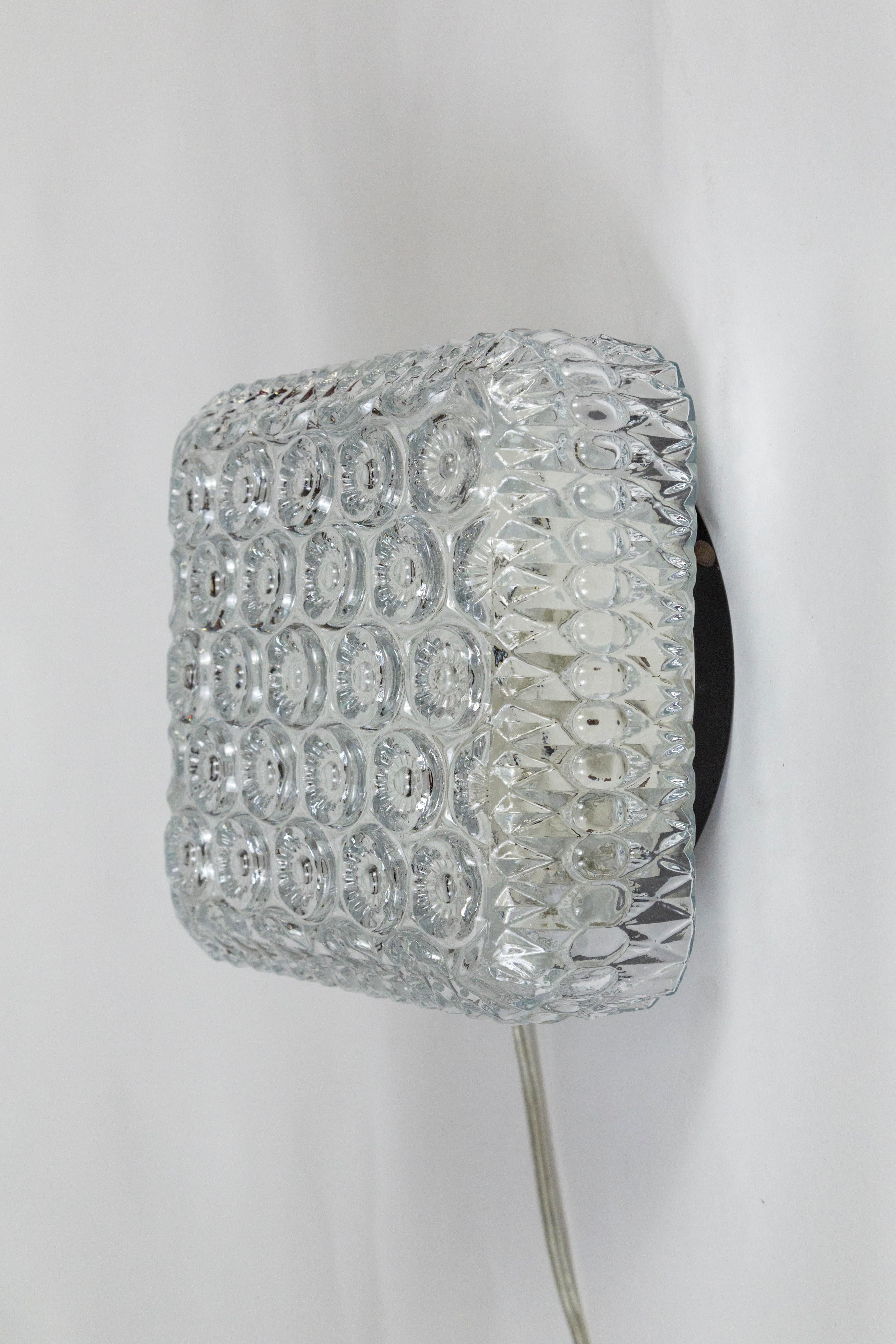 A beautifully designed, mid-century, molded glass flush mount light fixture in a square shape with round flower designs. The backplate is black on the rim and white on the inside; with a porcelain, medium base socket, newly wired. 8.5