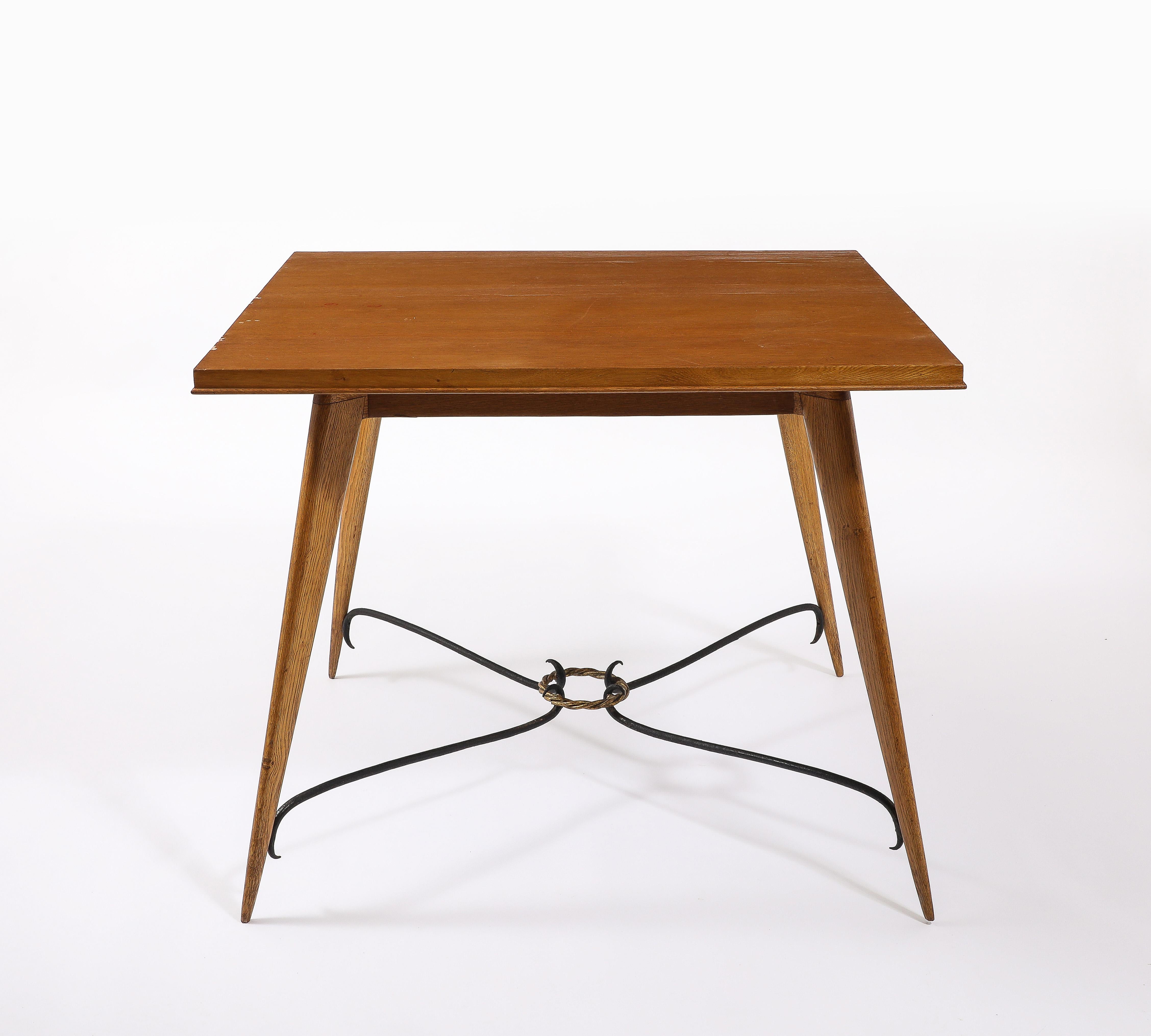 Light Oak square table with tapered legs joined by a scrolled wrought iron stretched held by a gilt ring.