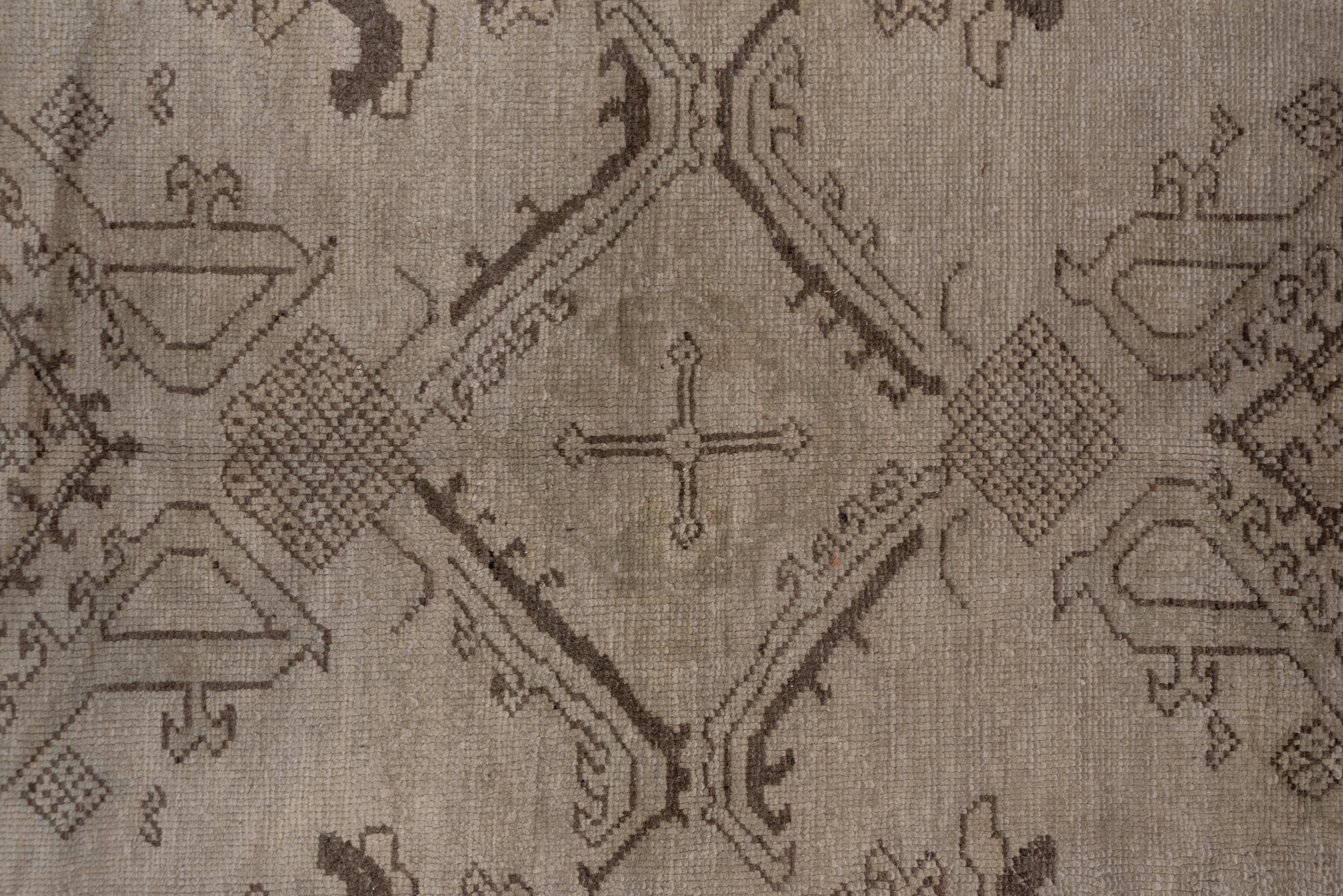 This carpet has a creamy beige field displays a Yaprak (Leaf) and ragged palmette pattern in three complete and two half-columns, accented in straw and rust-brown. The sandy-beige main border displays a quasi-Kufic pattern with enclosed small stars.