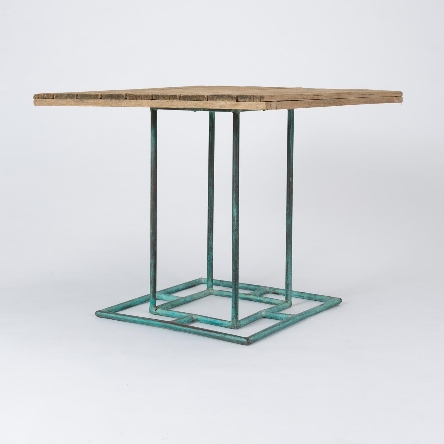 A model WT-2701 square patio table designed by Walter Lamb and manufactured by Brown Jordan. The table has a slatted surface in the original weathered wood, mounted on a bronze base. It’s subtle geometry suggests an Arts & Crafts sensibility, with
