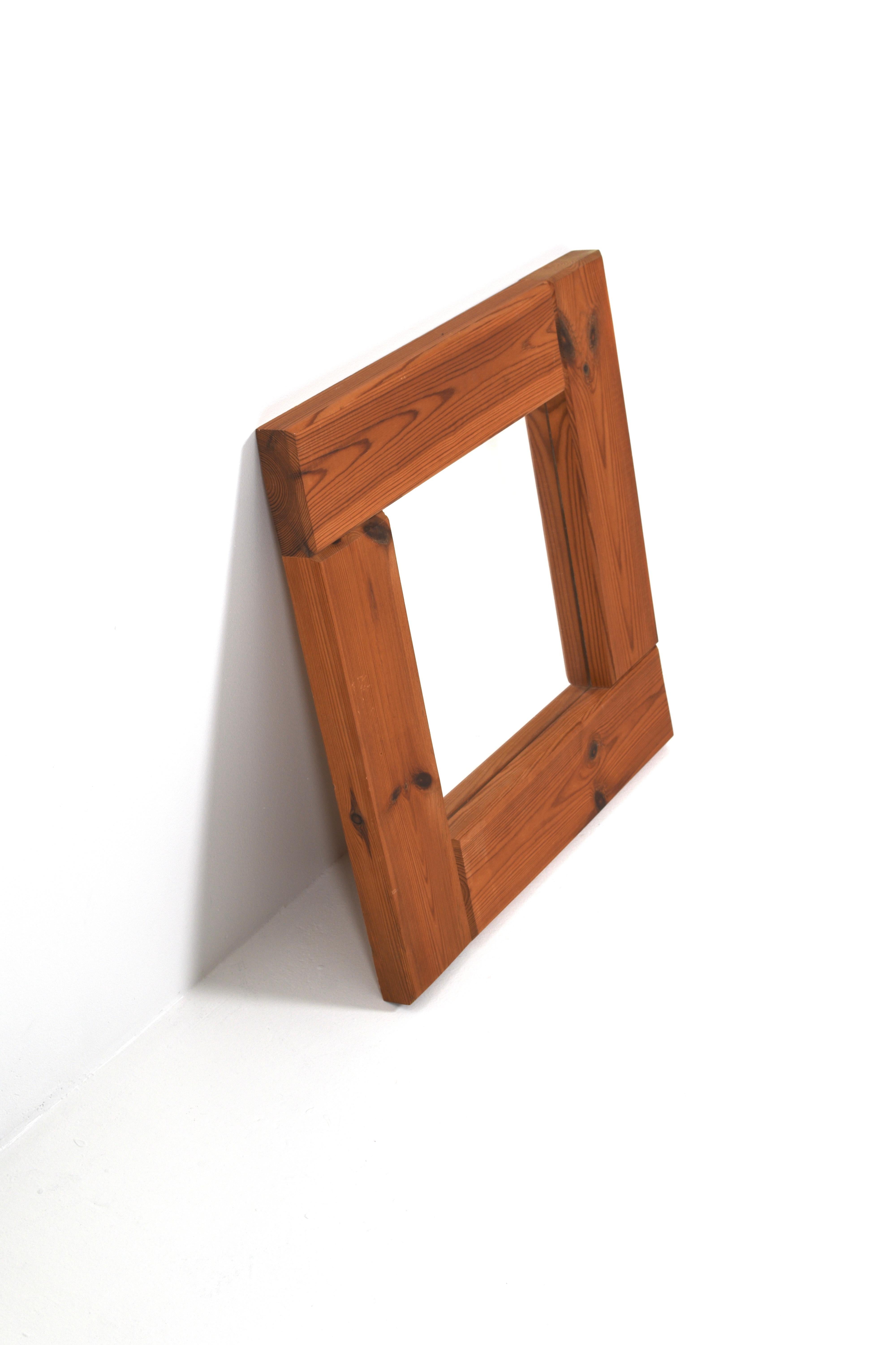 Specchio quadrato minimalista con un'audace cornice in pino rustico, realizzato in Svezia negli anni Settanta. Le venature naturali del legno e il tono caldo del pino conferiscono al pezzo un fascino scandinavo. La cornice misura 57 × 57 cm con un