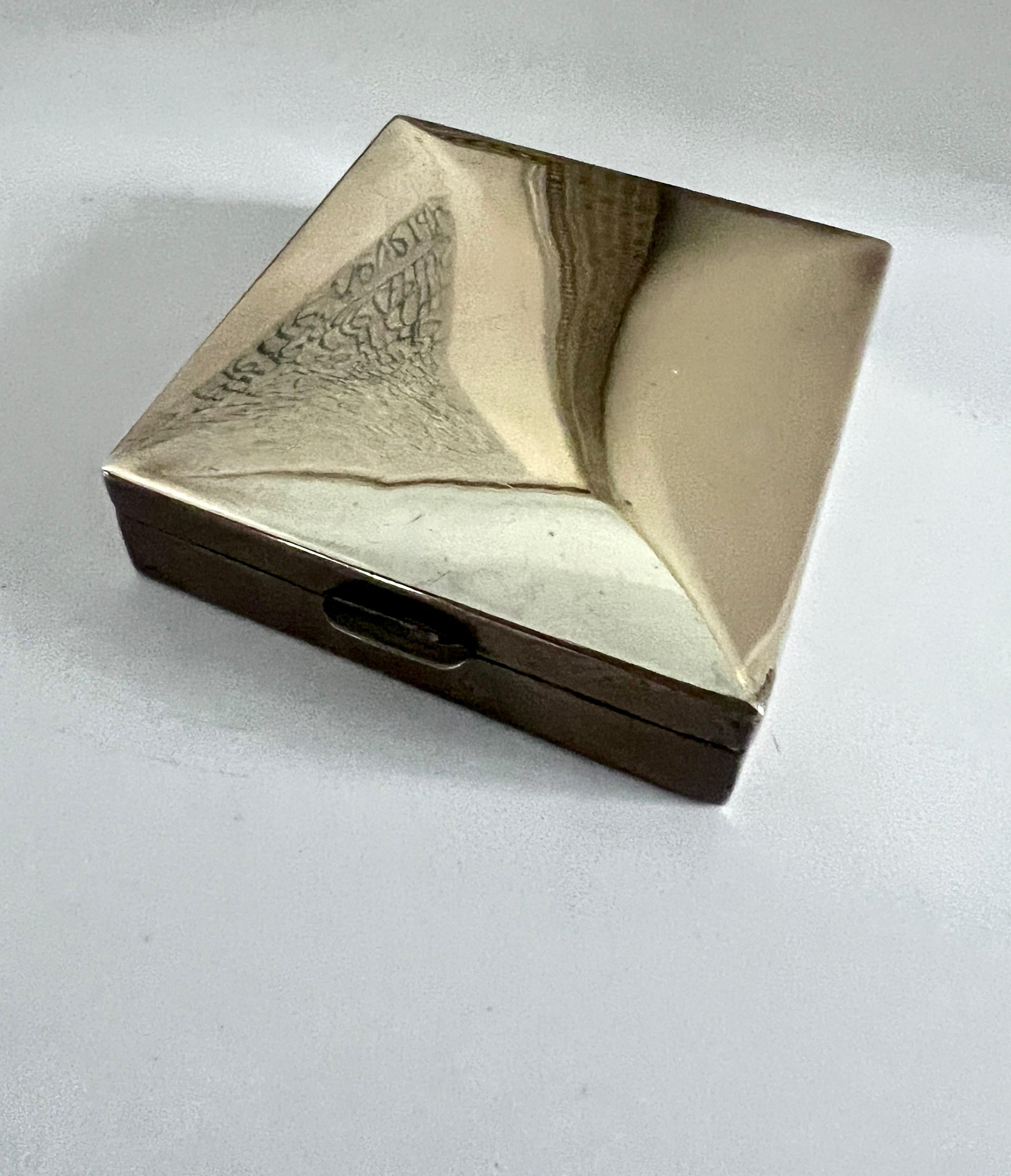 A square brass box with a slightly raised top.  The piece is lined with wood and green for office or work station supplies.  Also, a handsome decorative box on the cocktail table holding small things, from candies to 420.

A very nice box, in good