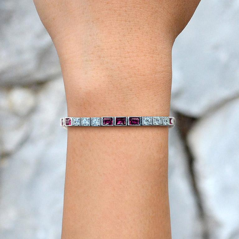 This stunning tennis bracelet features square rubies, each encircled by brilliant diamonds, set in 18K white gold. The bold, geometric Art Deco design creates a striking contrast between the deep red rubies and the sparkling diamonds. Crafted with