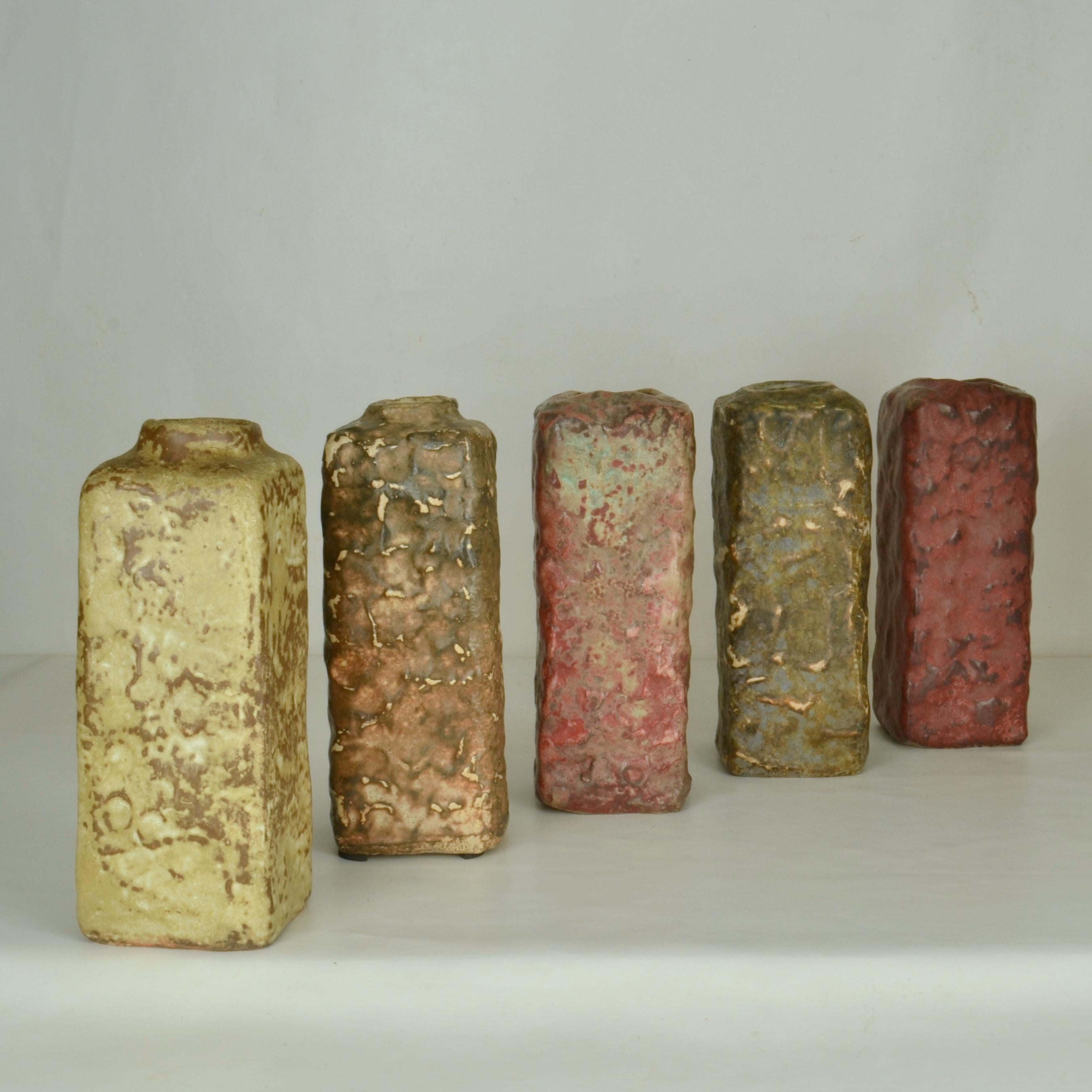 Five Mid-Century Modern square studio pottery vases glazed in natural earth tones that vary from dark red, grey-green to brown. They are hand formed and in different heights by Mobach's Dutch ceramist in the 1960's. 
The multi color glazes are made