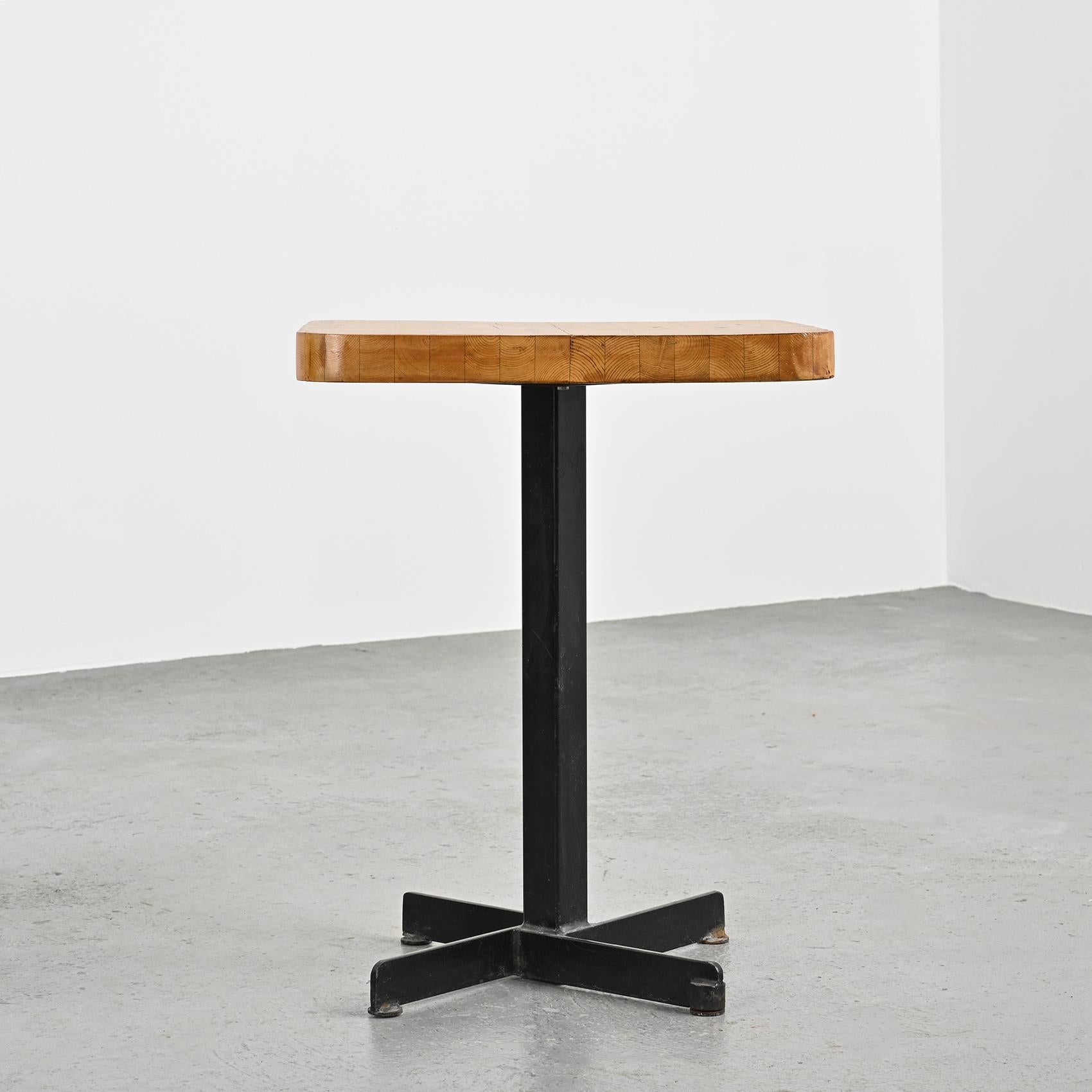 This iconic table from Charlotte Perriand has a very nice patina.

Designed in the 70s for the furnishment of the Nova and the Lauzières residences in Les Arcs 1800 in the French Alps, it is made out of a laminated pine squaretop and a cruciform