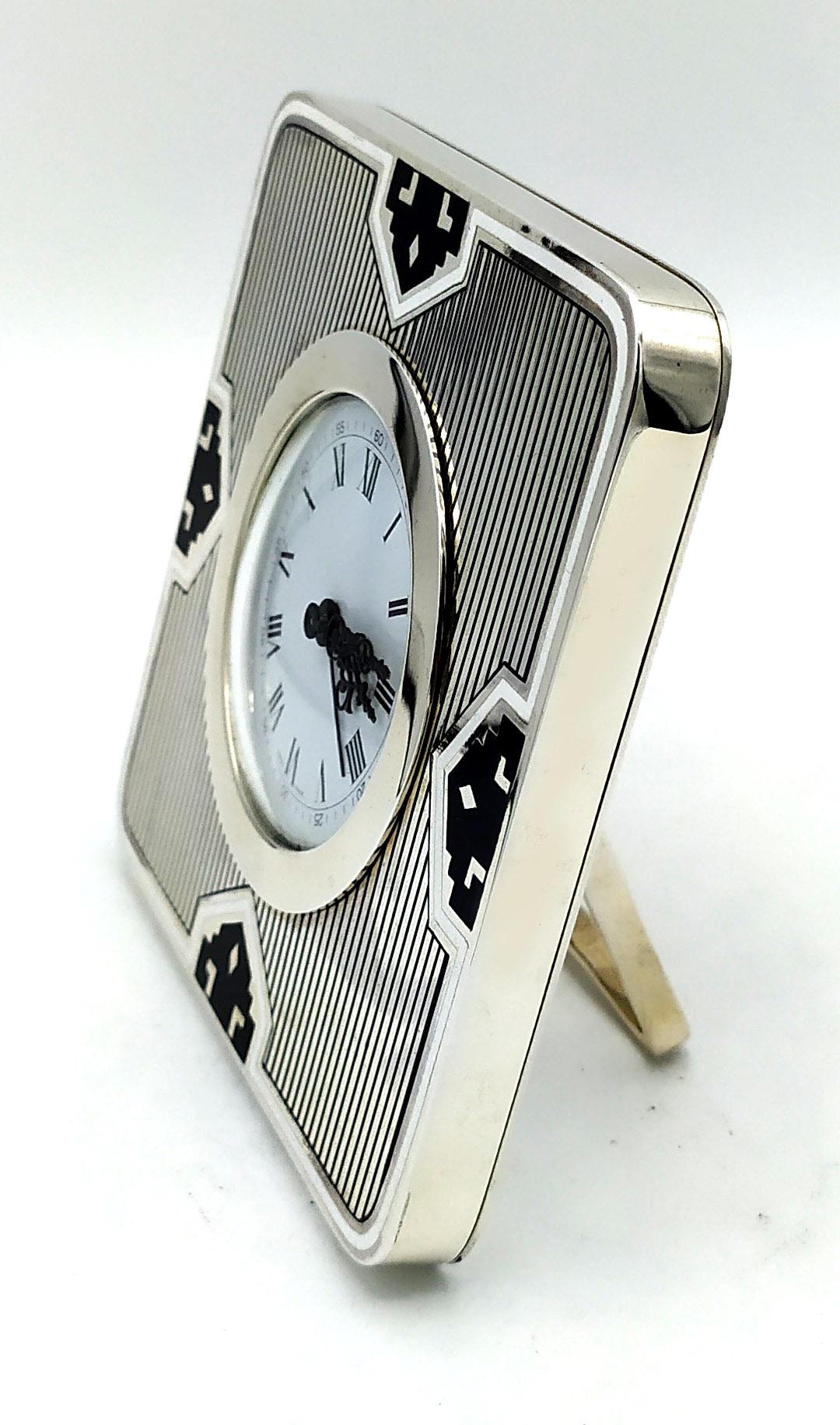 Square table clock with rounded corners in 925/1000 sterling silver with fire-enamelled Art Deco design. Dimensions cm. 11.8 x 11.8. Silver weight gr. 449. Swiss mechanical movement with 8-day charge and alarm. Designed by Giorgio Salimbeni in 1976