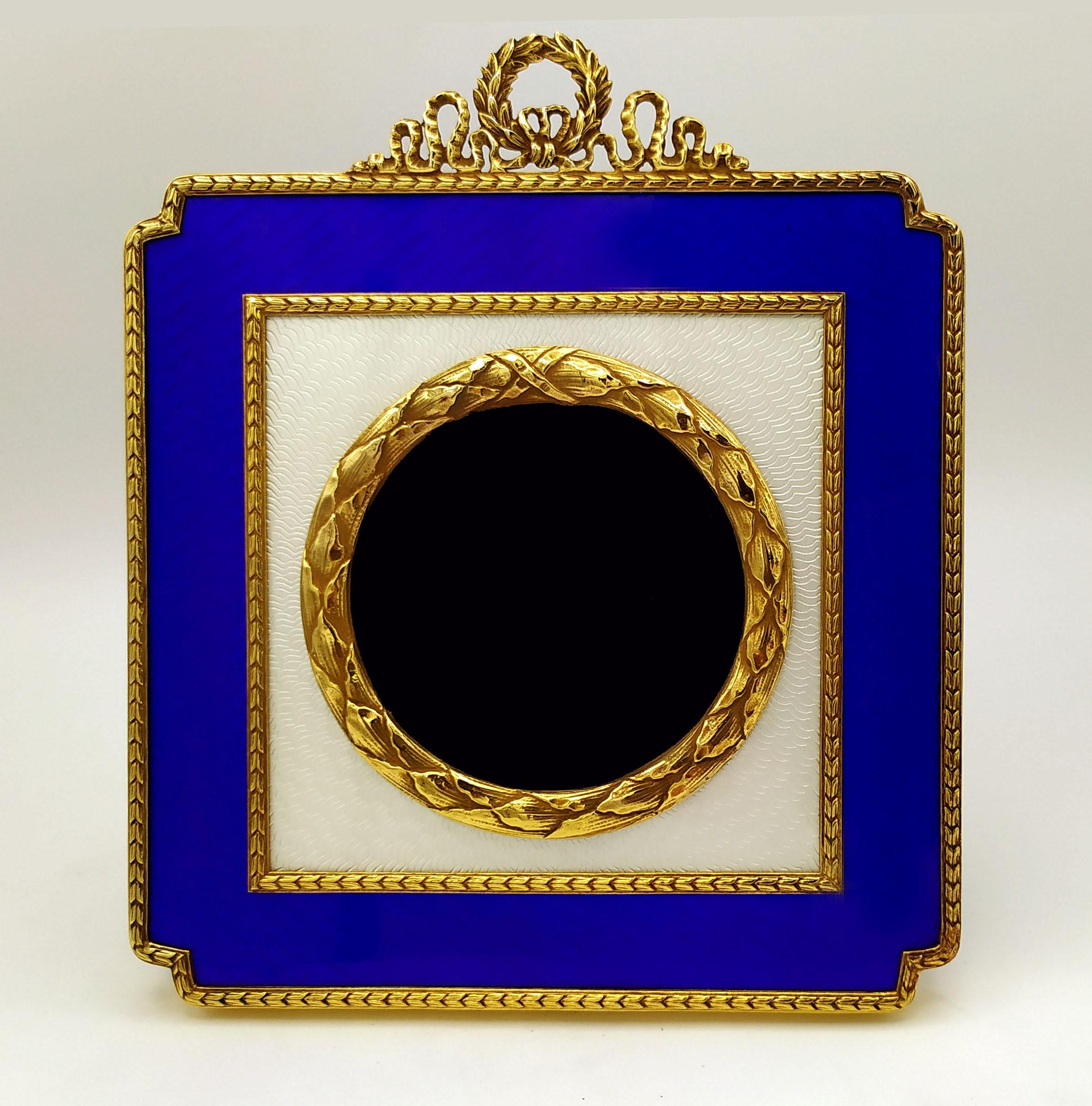 Square table frame for round photos diameter cm. 7, in 925/1000 sterling silver gold plated with translucent two-tone fired enamels on guillochè, with borders and ornaments in the French Empire Napoleon III style. External cm. 14.5 x 14.5. Weight