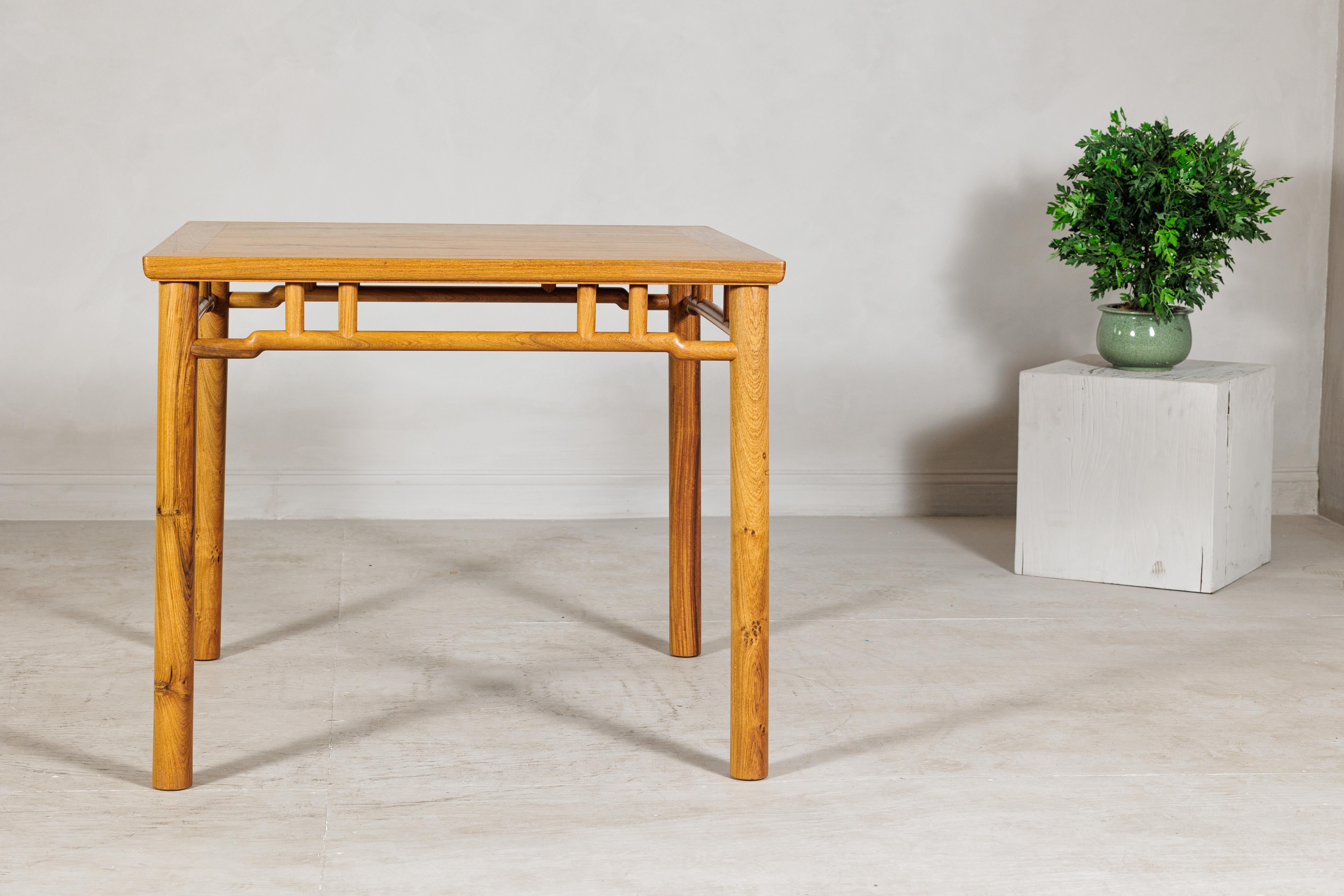This square side table is crafted in elmwood, a wood highly valued in Chinese furniture for its strength and expressive grain. The top reveals warm, honeyed tones and natural figuring that enliven the surface, bordered by a clean edge that