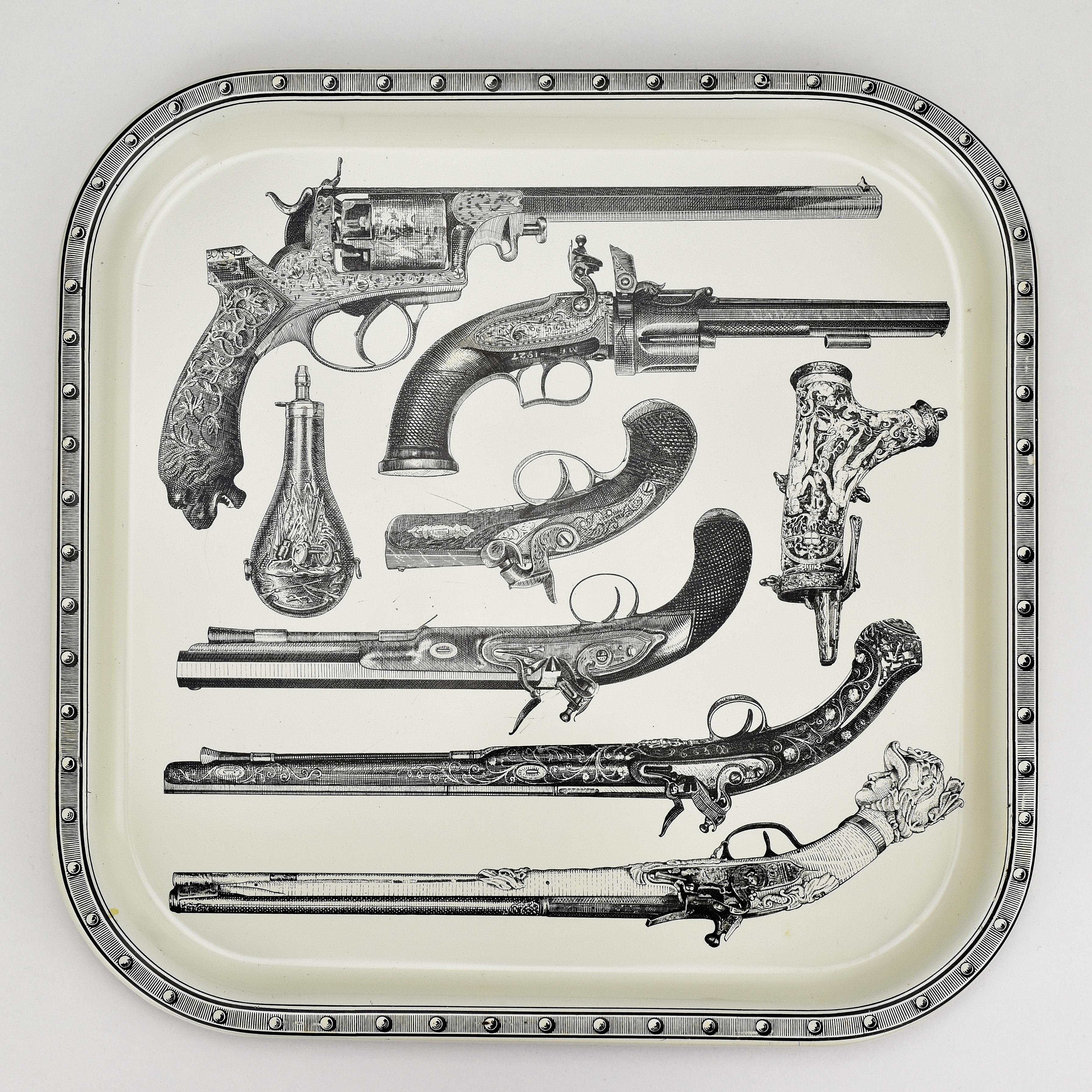 The vintage silkscreen printed metal tray designed by Piero Fornasetti in the 1960s features fine detailed depictions of guns spanning several centuries. The silkscreen printing technique imparts a classic touch, showcasing the detailed