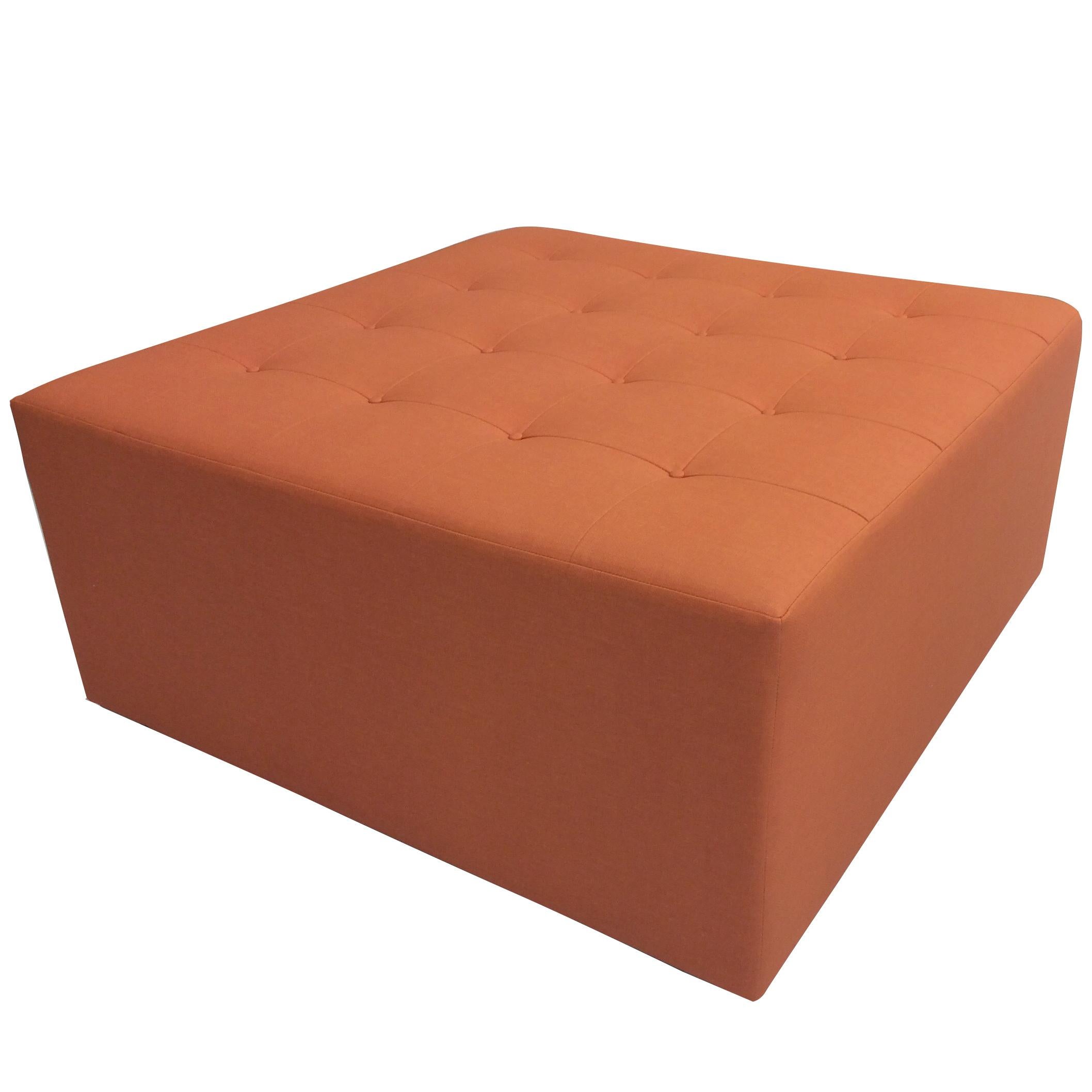 A large square ottoman with button tufted top and small block legs. The ottoman is shown in an orange vinyl fabric. Custom built to order and handmade at our studio in Norwalk, Connecticut. 

Measurement of ottoman shown: 18