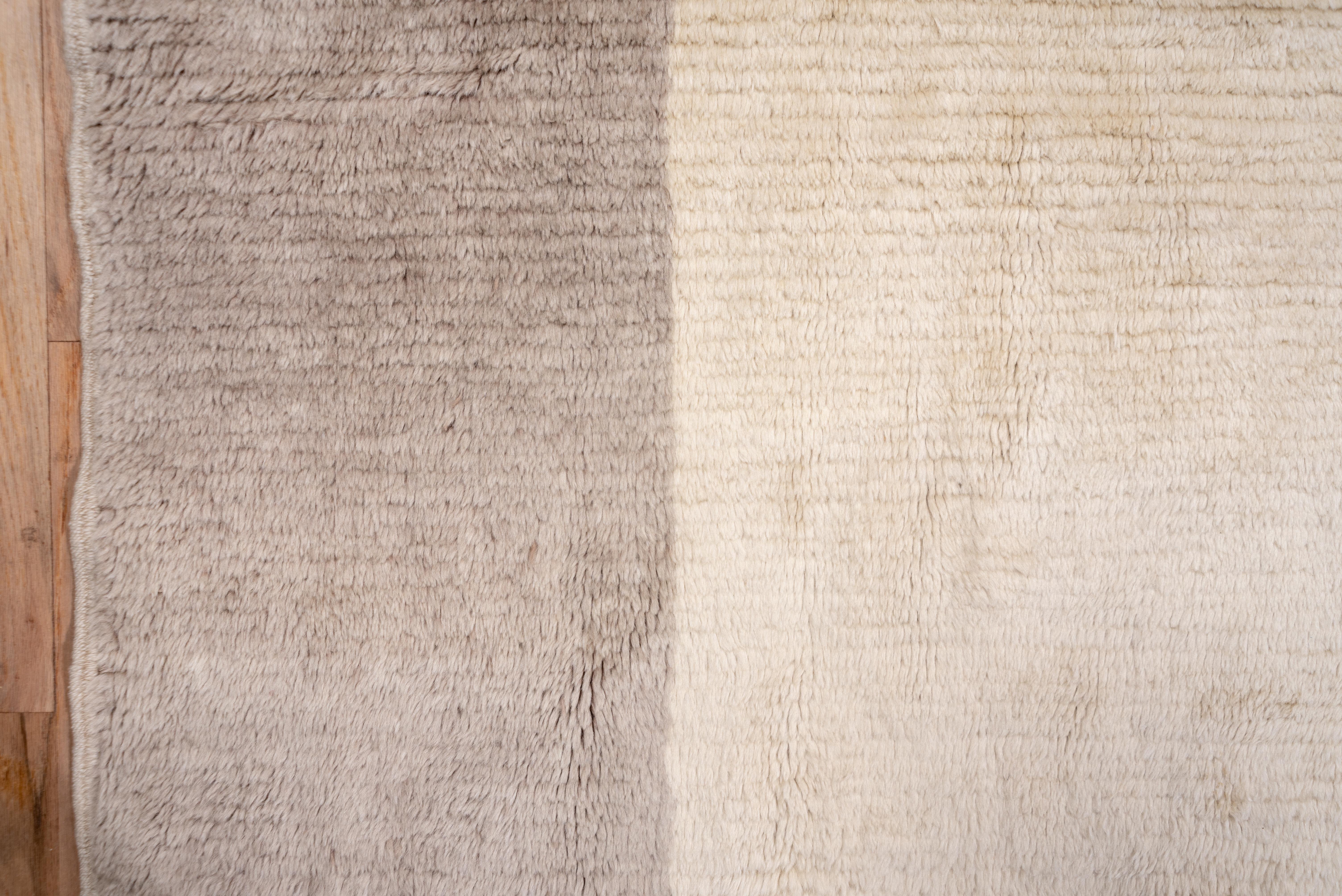 Two tones: a cream totally plain field is set within an equally plain warm grey wide border. Totally abstract, totally contemporary. The condition is excellent with a long, recumbent pile barely hiding the numerous wefts. On this central Turkish